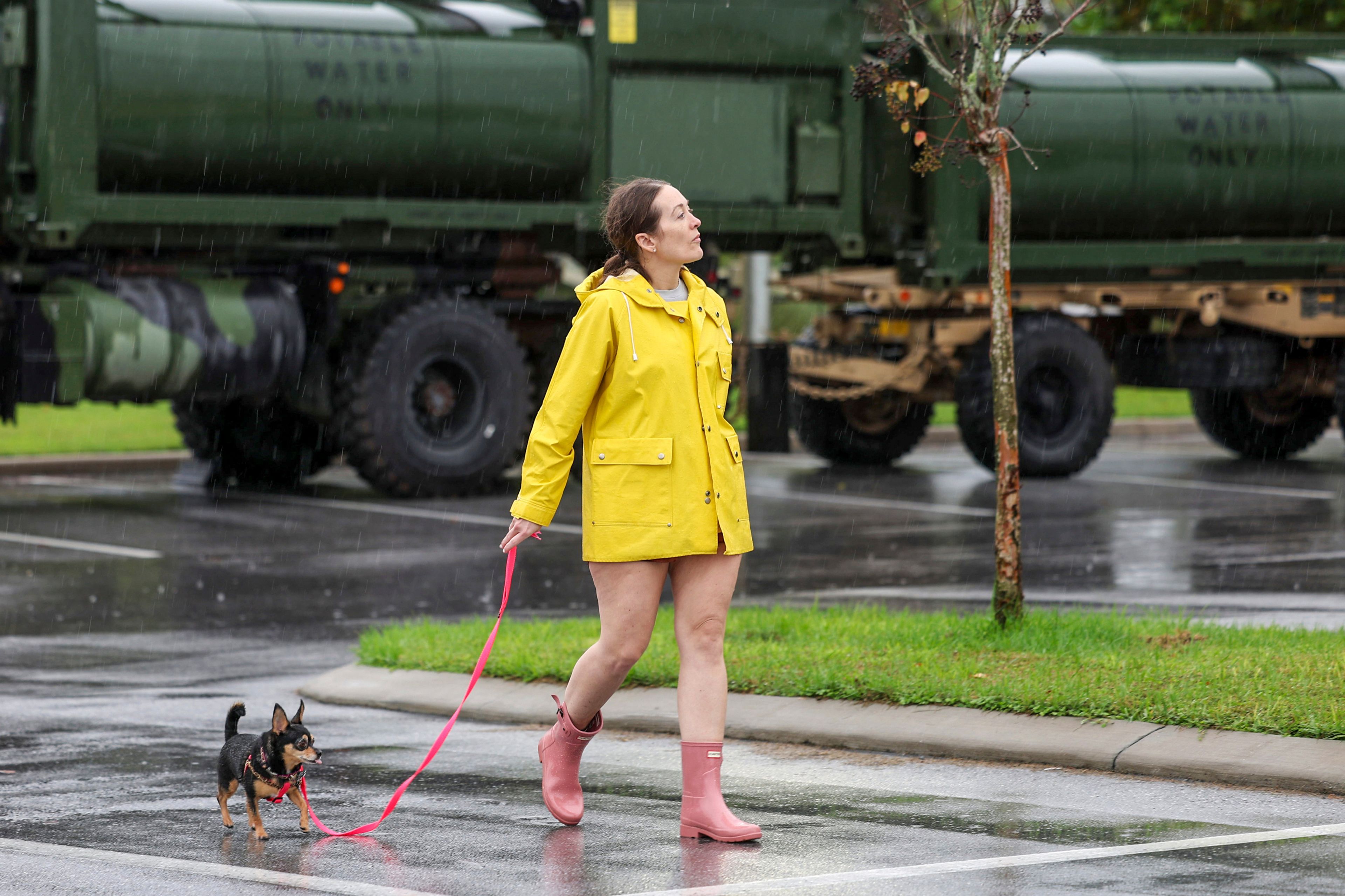 Erin Ferguson walks her dog while looking at equipment stationed by the Florida National Guard in preparation for Hurricane Milton in New Port Richey, Fla., Wednesday, Oct. 9, 2024. (AP Photo/Mike Carlson)