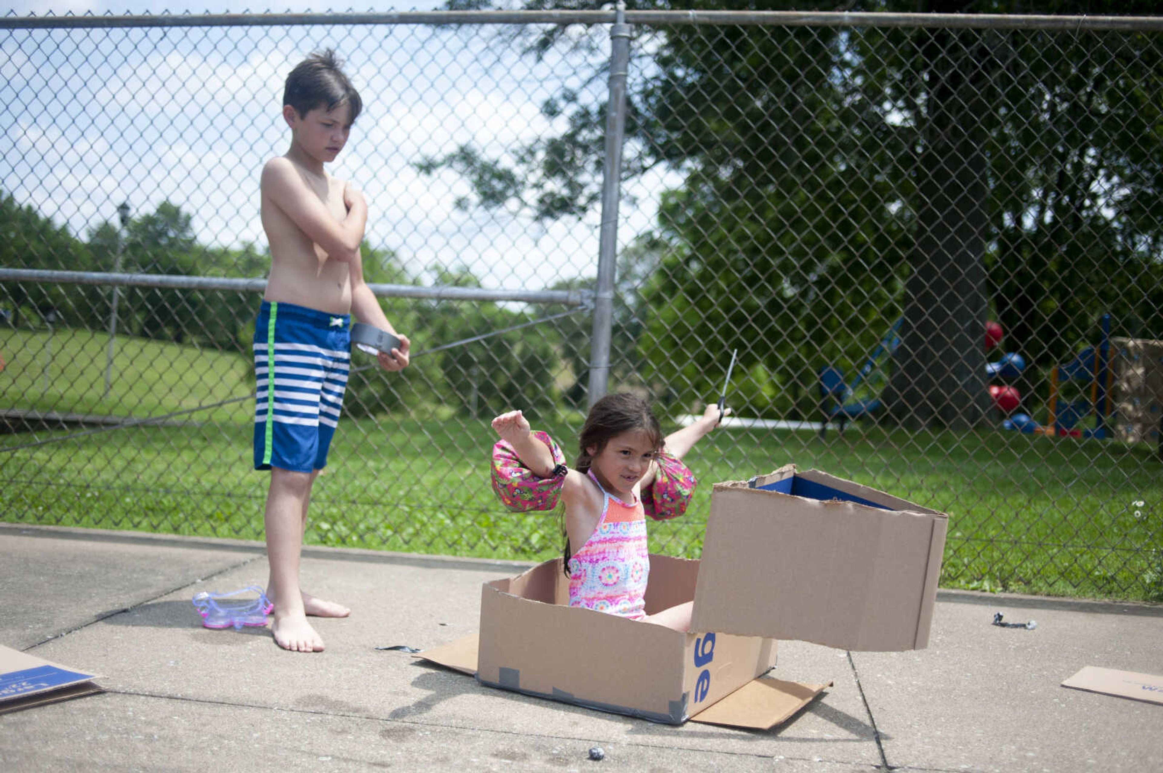 Georgia Riggs, formerly of Scott City and now Oak Ridge, 5, sits inside a cardboard boat next to her brother Weston Riggs, 9, as they prepare the boat for a contest during a free pool party to start off the 2019 season Saturday, May 25, 2019, at the&nbsp;Scott City Community Pool.