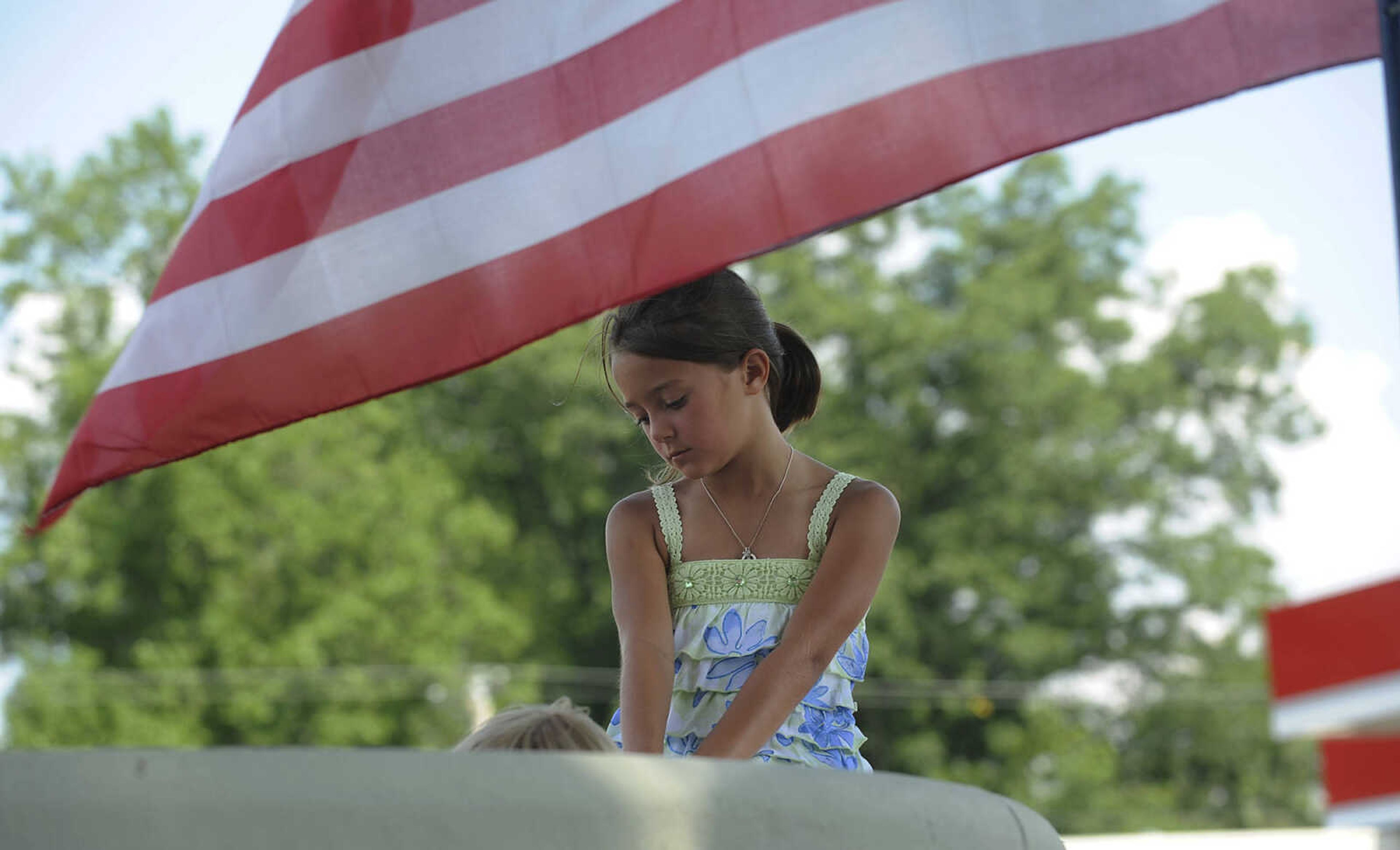 Rhiannon Henderson, 7, sits on the veterans memorial during the celebration in honor of the centennial of the Scott County Courthouse in Benton Saturday, June 16. The building, the sixth courthouse for Scott County, was designed by Henry H. Hohenschild in 1912 and dedicated on April 20, 1914.  The courthouse was placed on the National Register of Historic Places in January 2004.