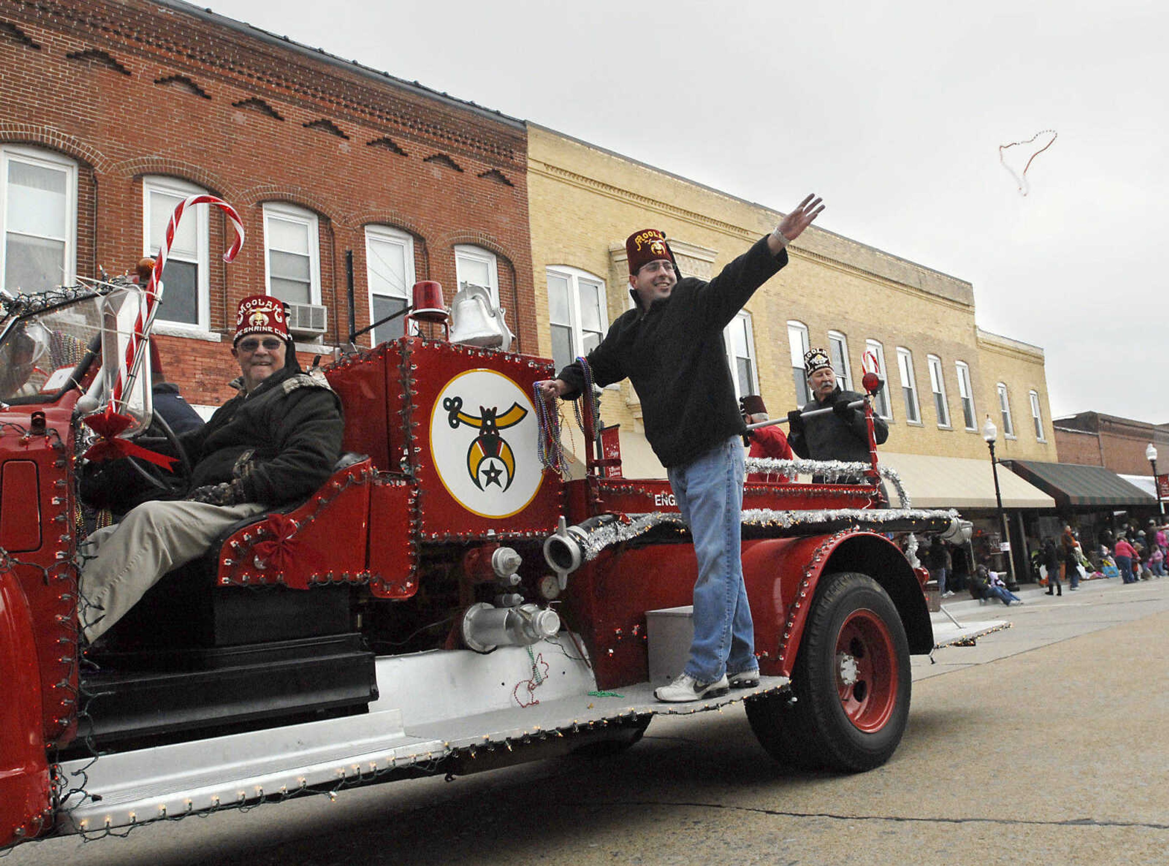 KRISTIN EBERTS ~ keberts@semissourian.com

John Bremer throws out bead necklaces as Dave McLain, left, drives the Cape Shrine Club float during the Jackson Christmas Parade on Saturday, Dec. 4, 2010, in downtown Jackson.