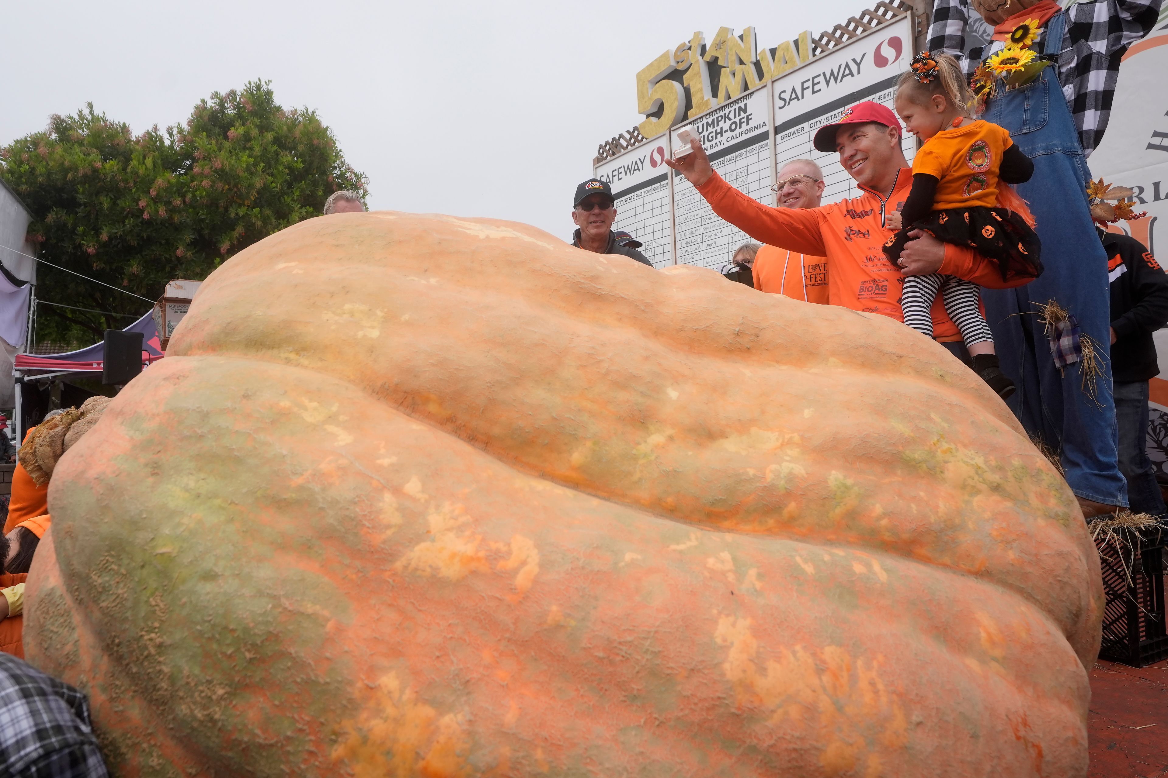 Travis Gienger, of Anoka, Minn., second from right, celebrates with his daughter Lily, 3, after his pumpkin weighed in at 2,471 pounds to win at the Safeway World Championship Pumpkin Weigh-Off in Half Moon Bay, Calif., Monday, Oct. 14, 2024. (AP Photo/Jeff Chiu)