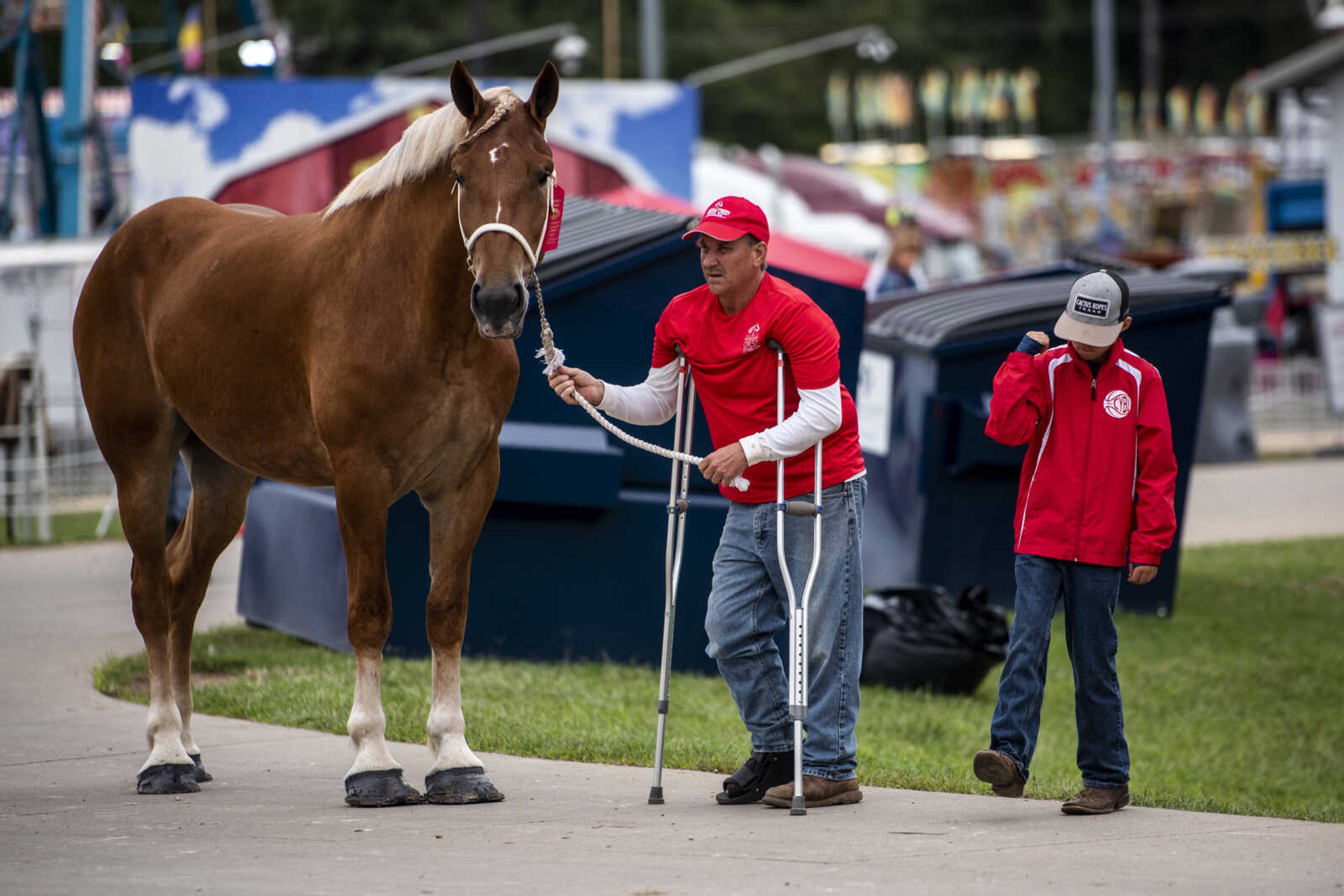 Dierks Simmons, 11, right, dances while standing next to David Kluesner, center, as he holds the lead of Belgian draft horse Amanda, who took second place in the 2-year-old draft horse class at the SEMO District Fair Sunday, Sept. 9, 2018 in Cape Girardeau.