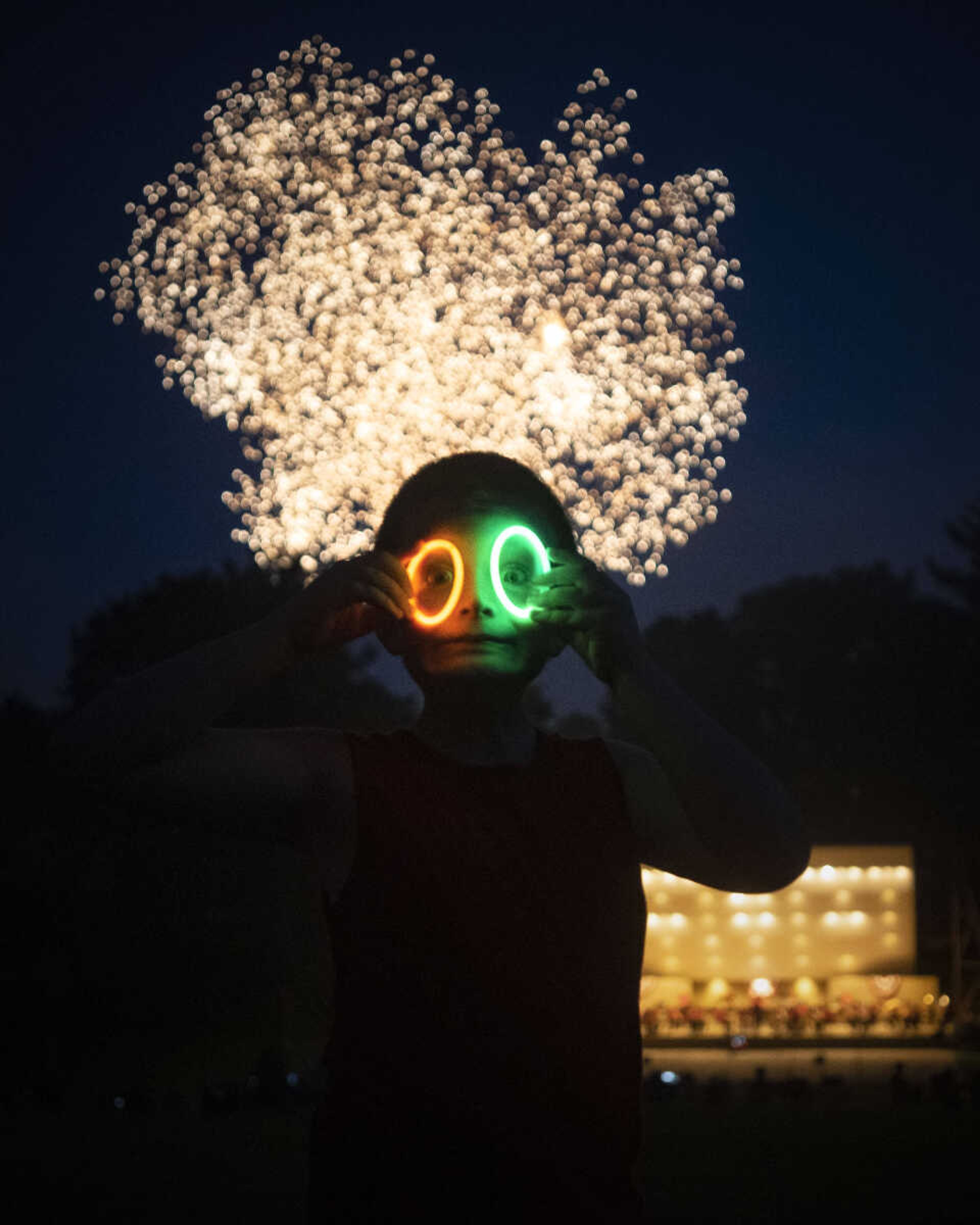 Wesley Puckett, 7, is backlit by an exploding firework while making a silly face with glow bracelets during an Independence Day celebration at the Jackson Municipal Band Shell.