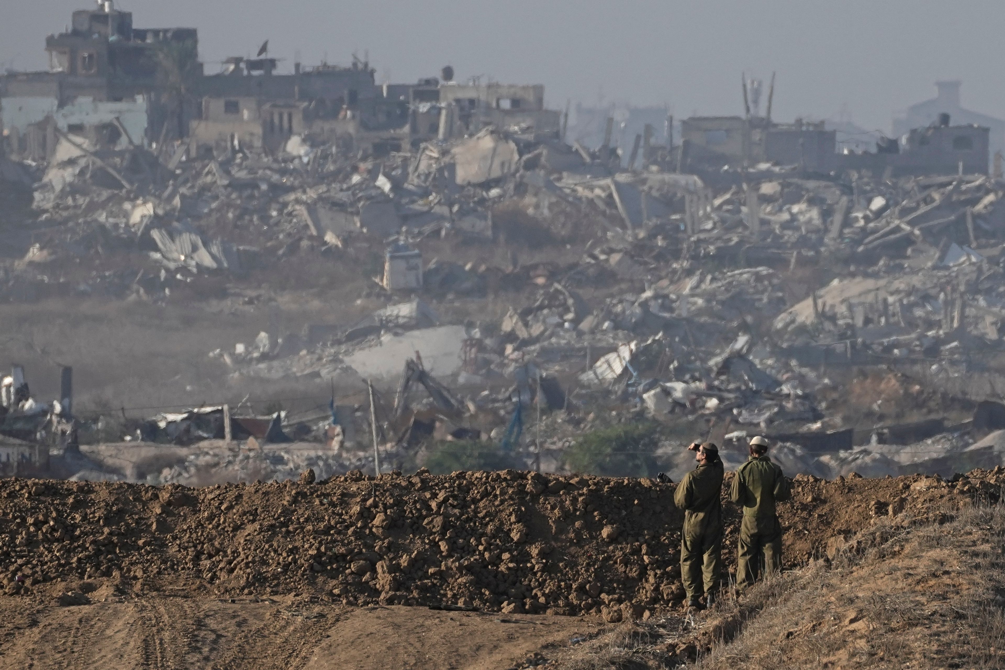 Israeli soldiers look at a destroyed part of Gaza City from their position at the Israel-Gaza border, as seen from southern Israel, Sunday Dec. 1, 2024. (AP Photo/Tsafrir Abayov)