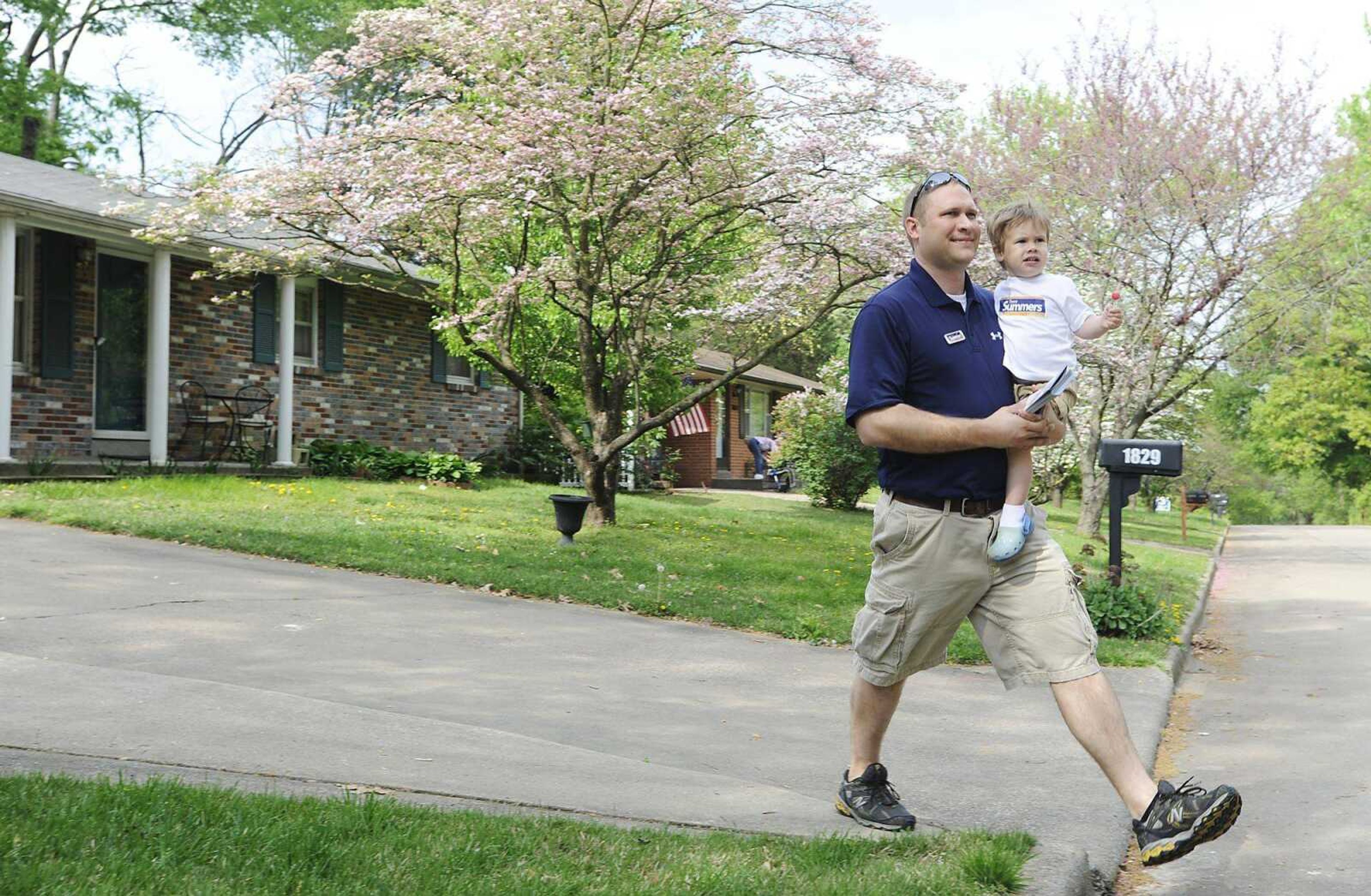 Cape Girardeau City Council Ward 3 candidate Trent Summers walks down Georgia Street in Cape Girardeau with his son Clark, 1, Saturday, March 31. Summers was canvassing the neighborhood introducing himself to potential voters. (ADAM VOGLER)