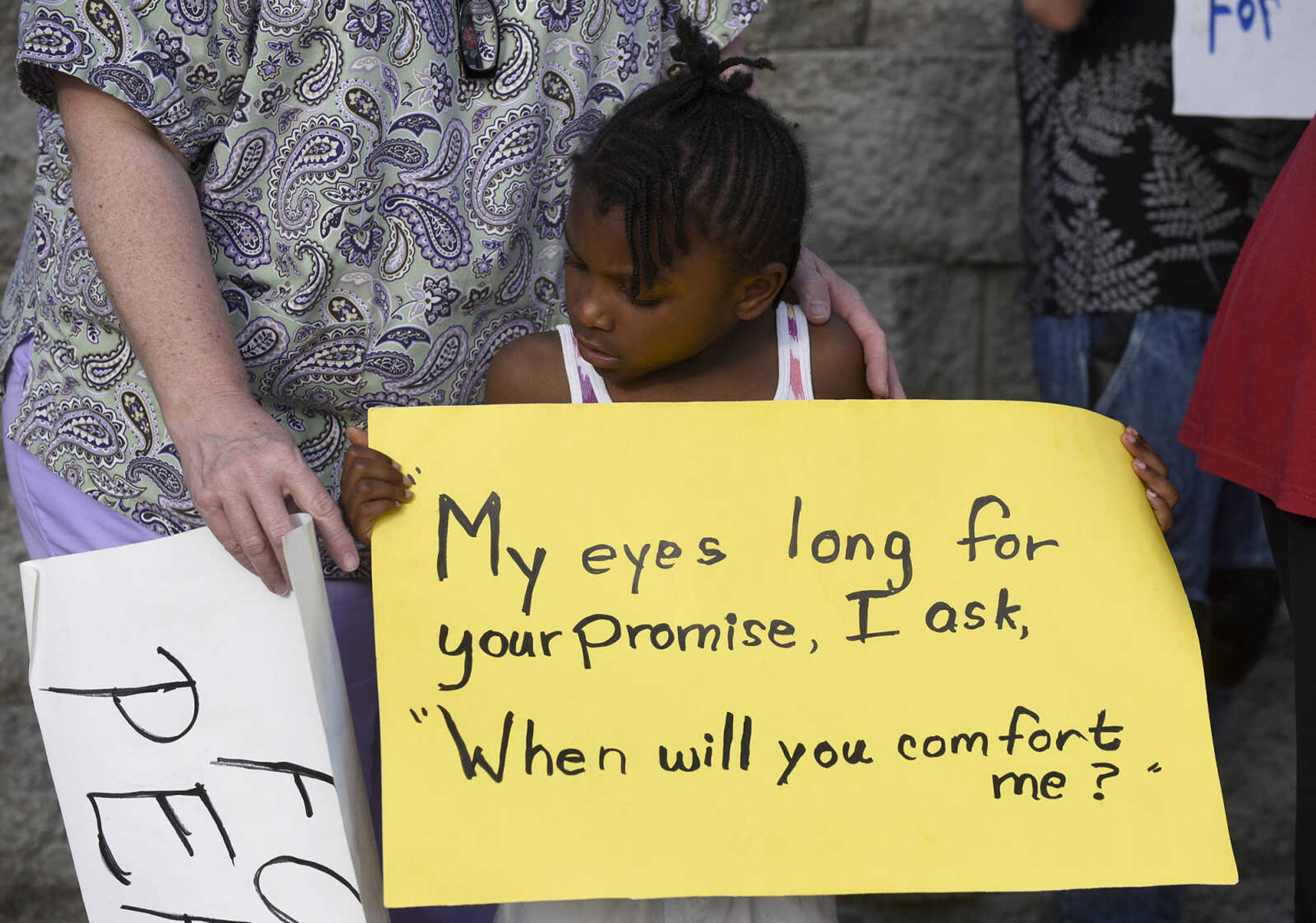 Kaye Hood helps Serenity Anderson, 5, hold a sign during a Stop Needless Acts of Violence Please(SNAP) community prayer on Tuesday, May 16, 2017, at the corner of Independence Street and Henderson Ave. in Cape Girardeau.