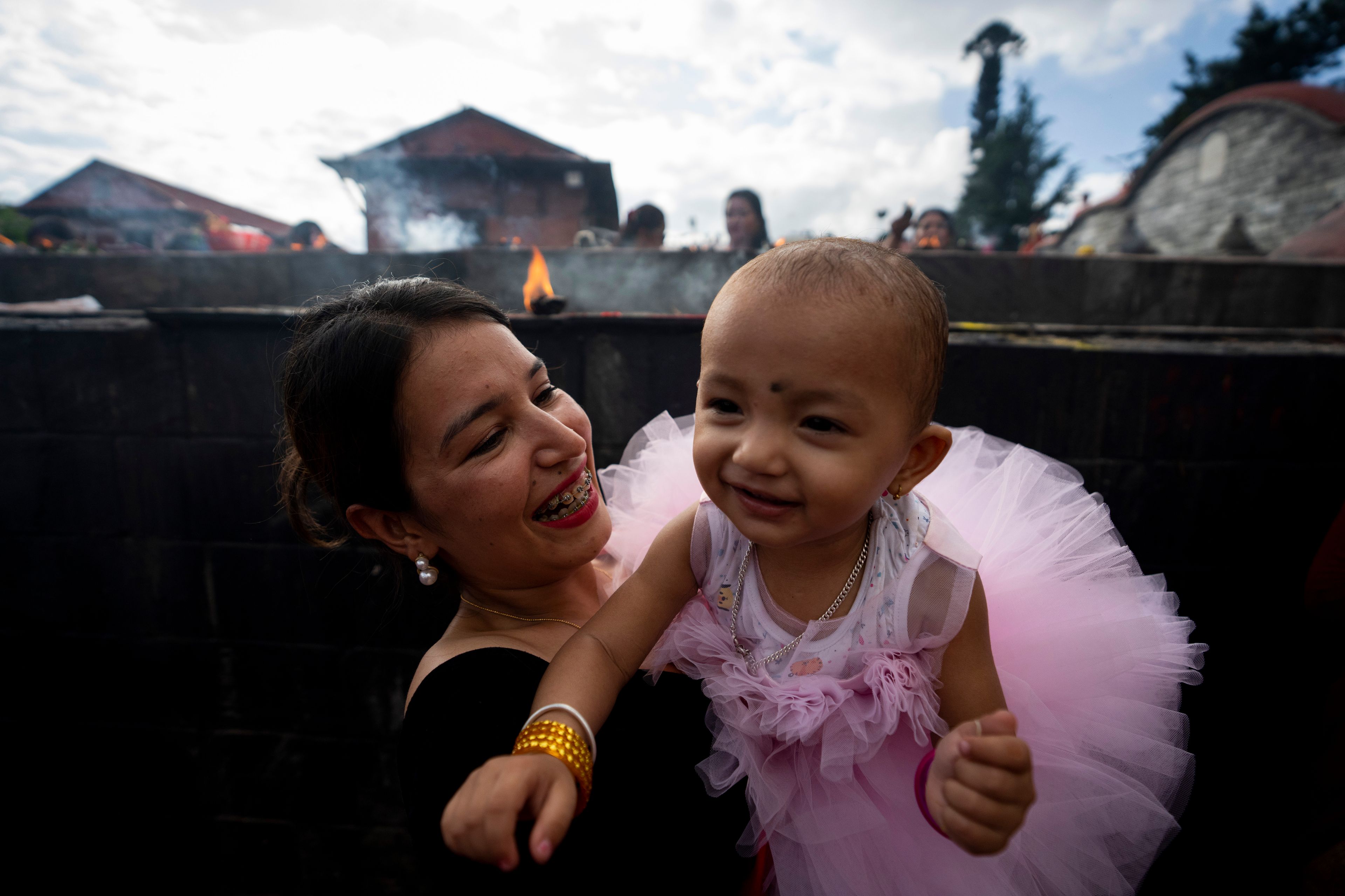 A woman plays with her child at the Pashupatinath temple during Teej festival celebrations in Kathmandu, Nepal, Friday, Sept. 6, 2024. (AP Photo/Niranjan Shrestha)