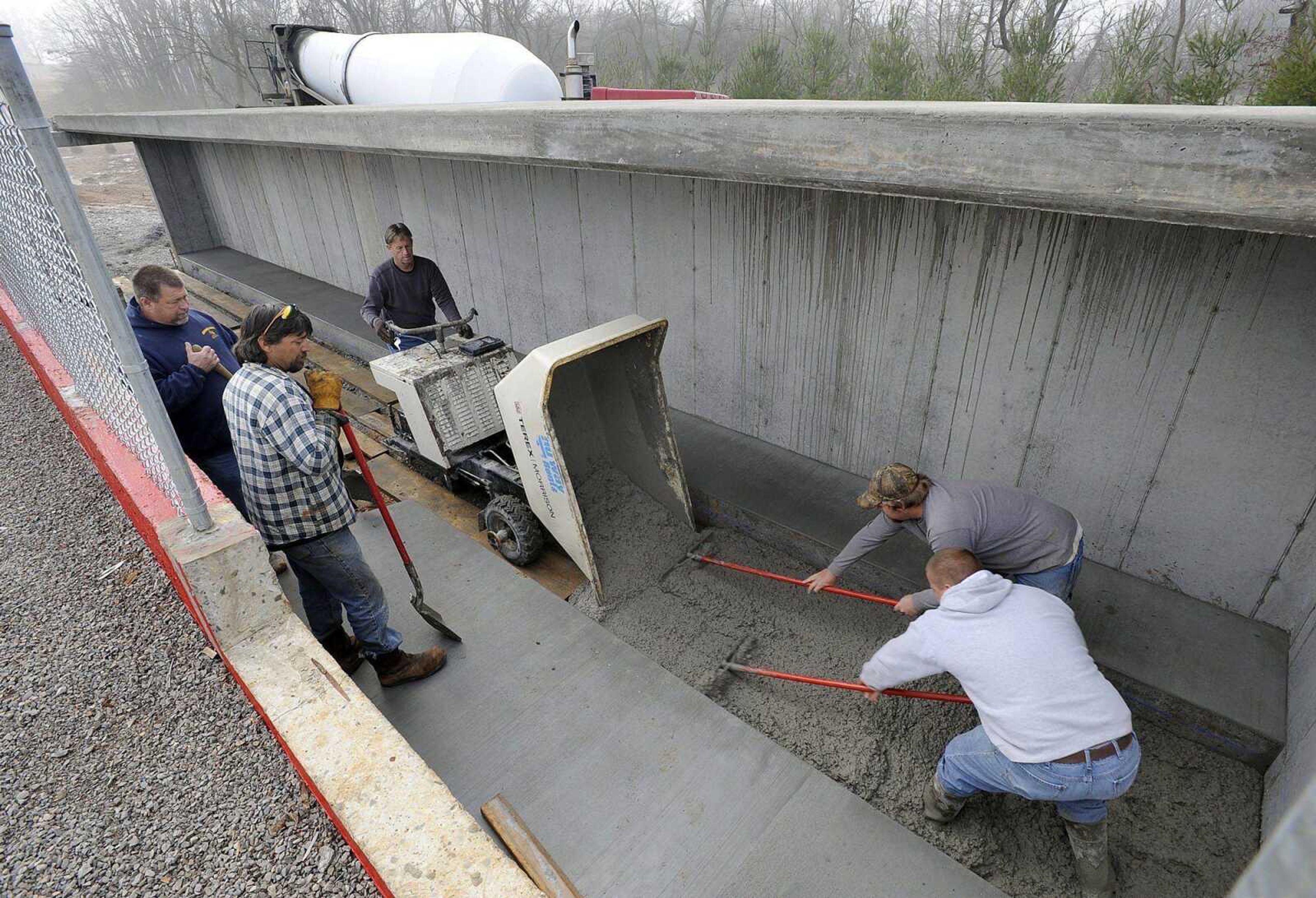 Ron Clark, back left, and his crew pour concrete in the visitors dugout Tuesday at the new Whitey Herzog Stadium in Jackson.