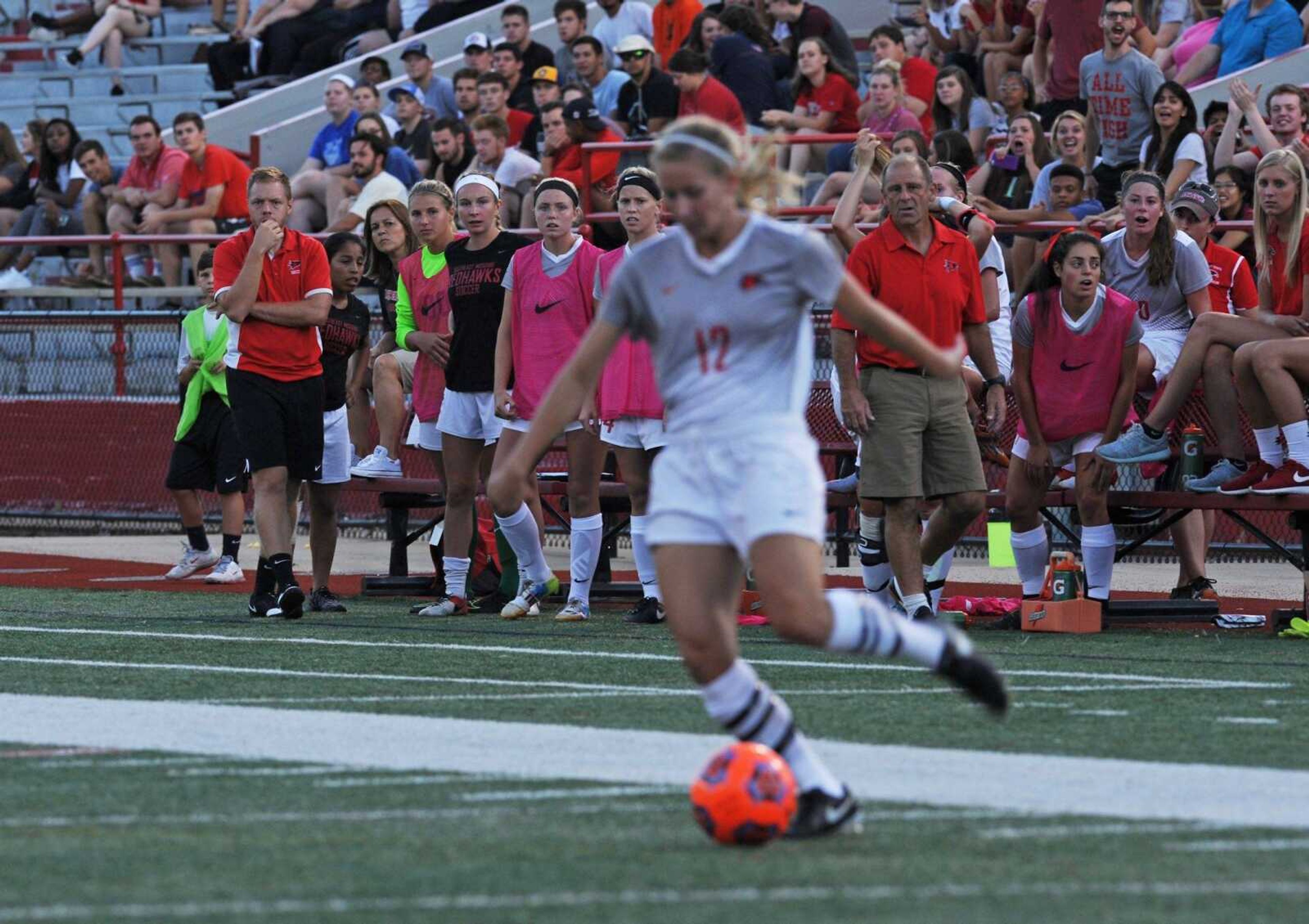 The Southeast Missouri State bench looks on as freshman striker Cassidi Tomsu, a Jackson alum, crosses the ball into the box in the first half  of Sunday night's game at Houck Stadium. Tomsu scored her first collegiate goal in the Redhawks' 3-1 victory over Illinois Springfield.