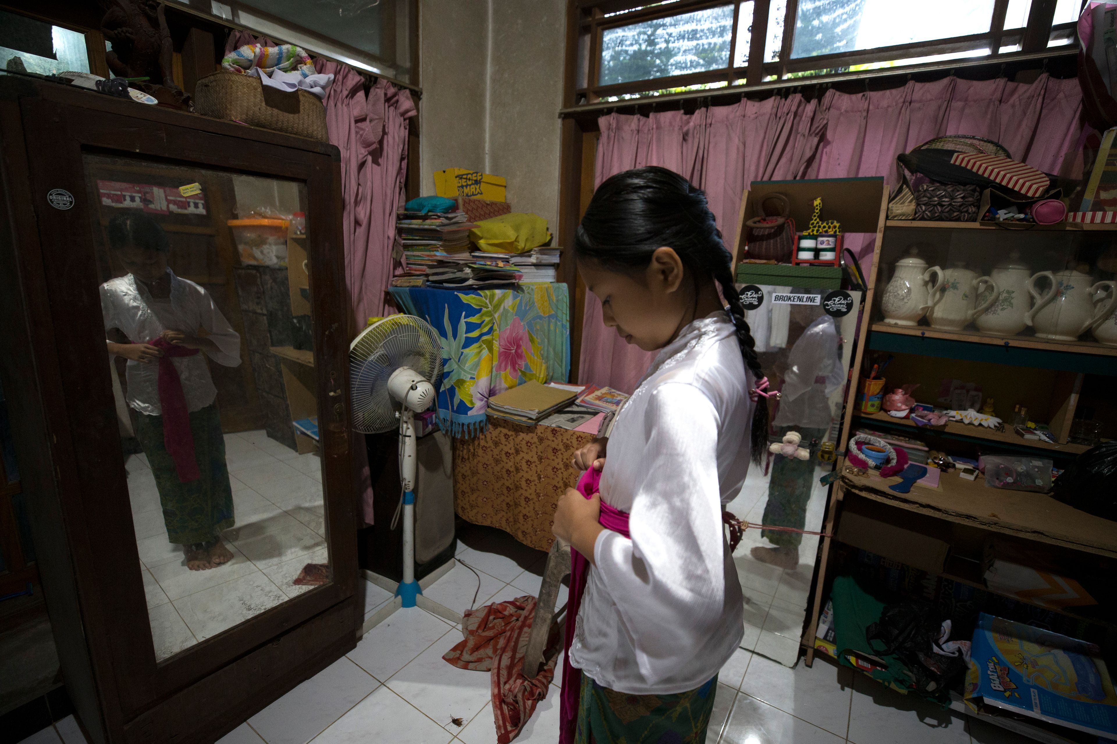 Ketut Nita Wahyuni, 11, prepares for school at her home in Geriana Kauh village, Karangasem, Bali, Indonesia on Thursday, Nov. 21, 2024. (AP Photo/Firdia Lisnawati)