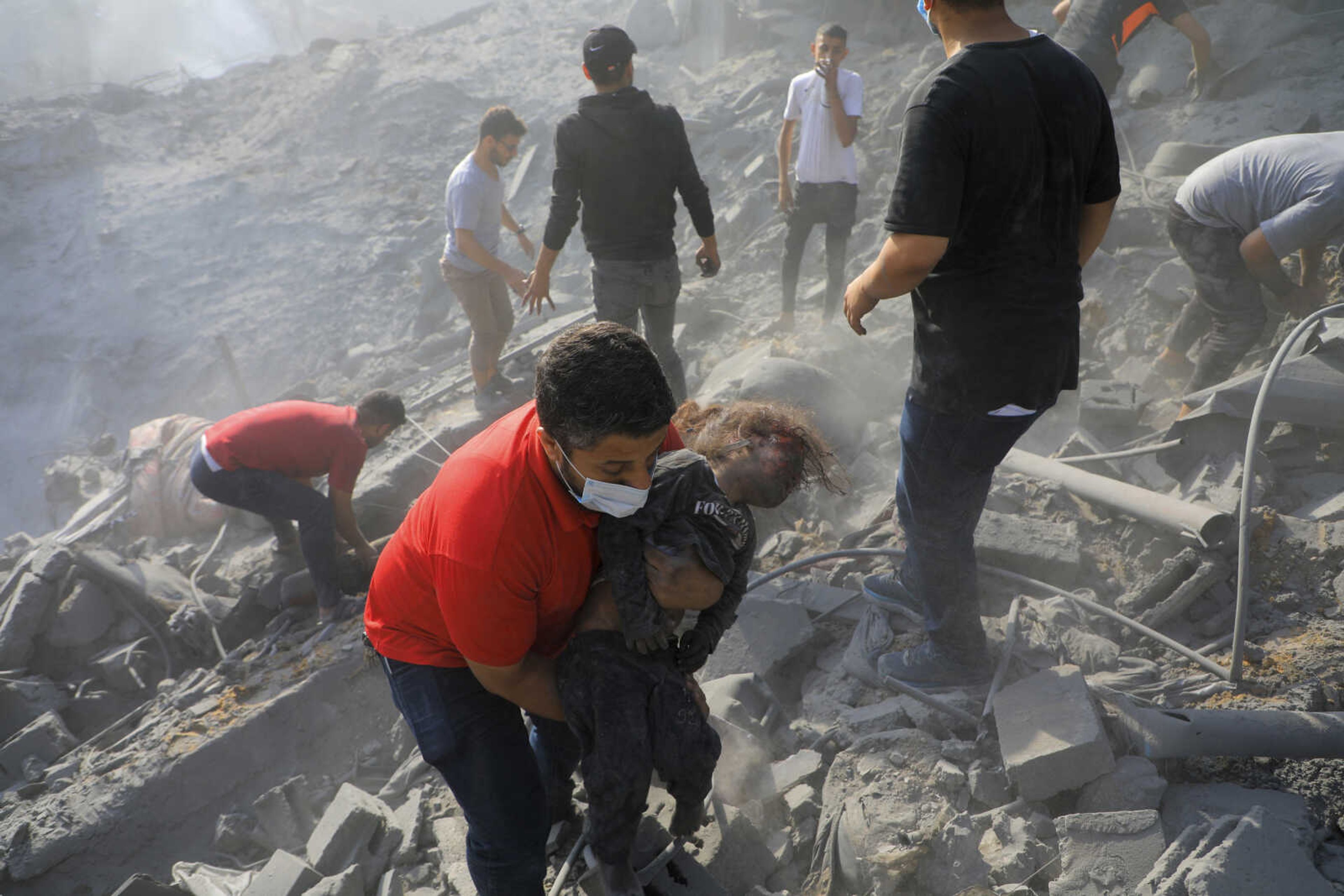 A Palestinian man carries a dead child as others look for survivors among the rubble of destroyed buildings Tuesday following Israeli airstrikes on Jabaliya refugee camp on the outskirts of Gaza City.