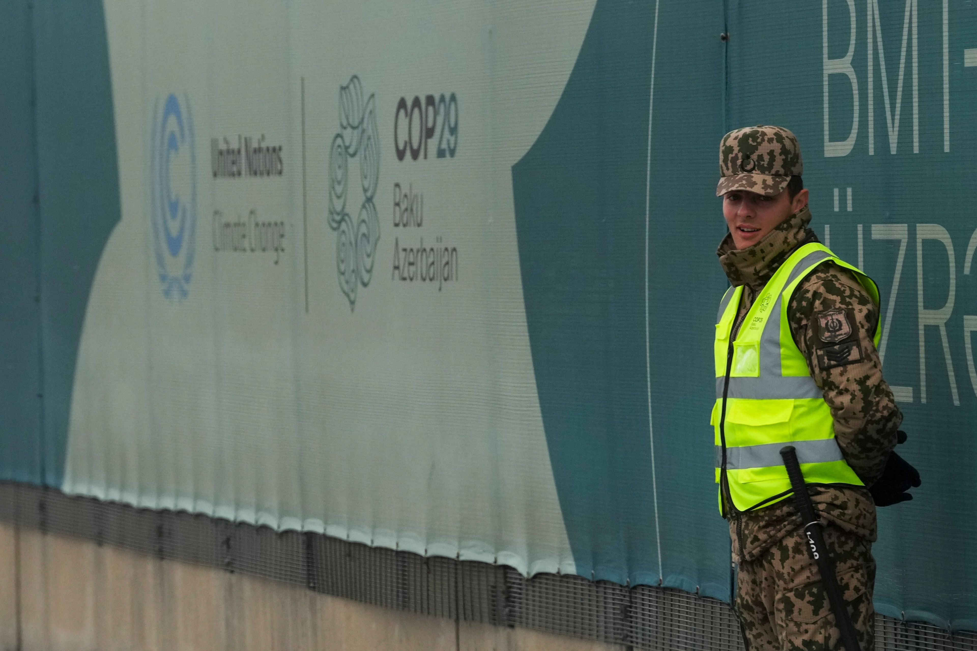 A security person stands near a logo for the COP29 U.N. Climate Summit, Thursday, Nov. 21, 2024, in Baku, Azerbaijan. (AP Photo/Peter Dejong)