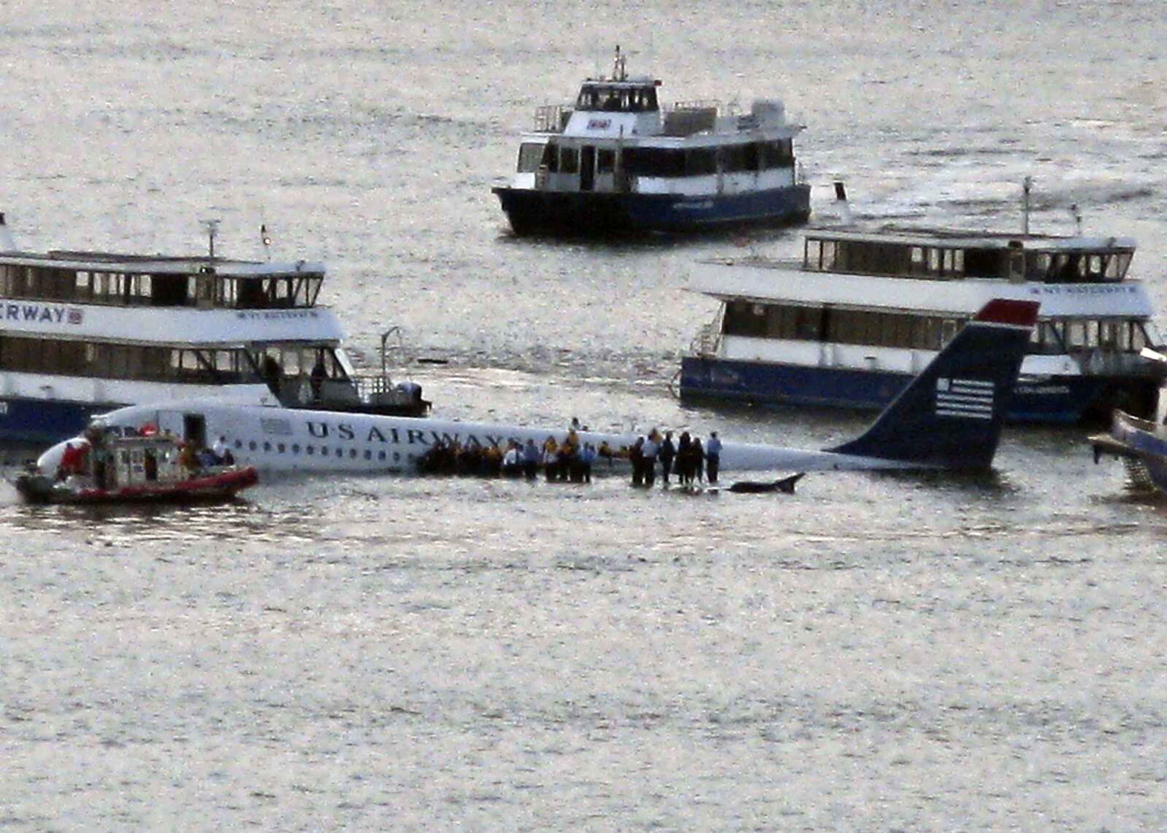 Airline passengers wait to board boats to be rescued on the wings of a US Airways Airbus 320 jetliner that safely ditched in the frigid waters of the Hudson River in New York, Thursday Jan. 15, 2009 after a flock of birds knocked out both its engines. All 155 people on board survived. (AP Photo/Steven Day)