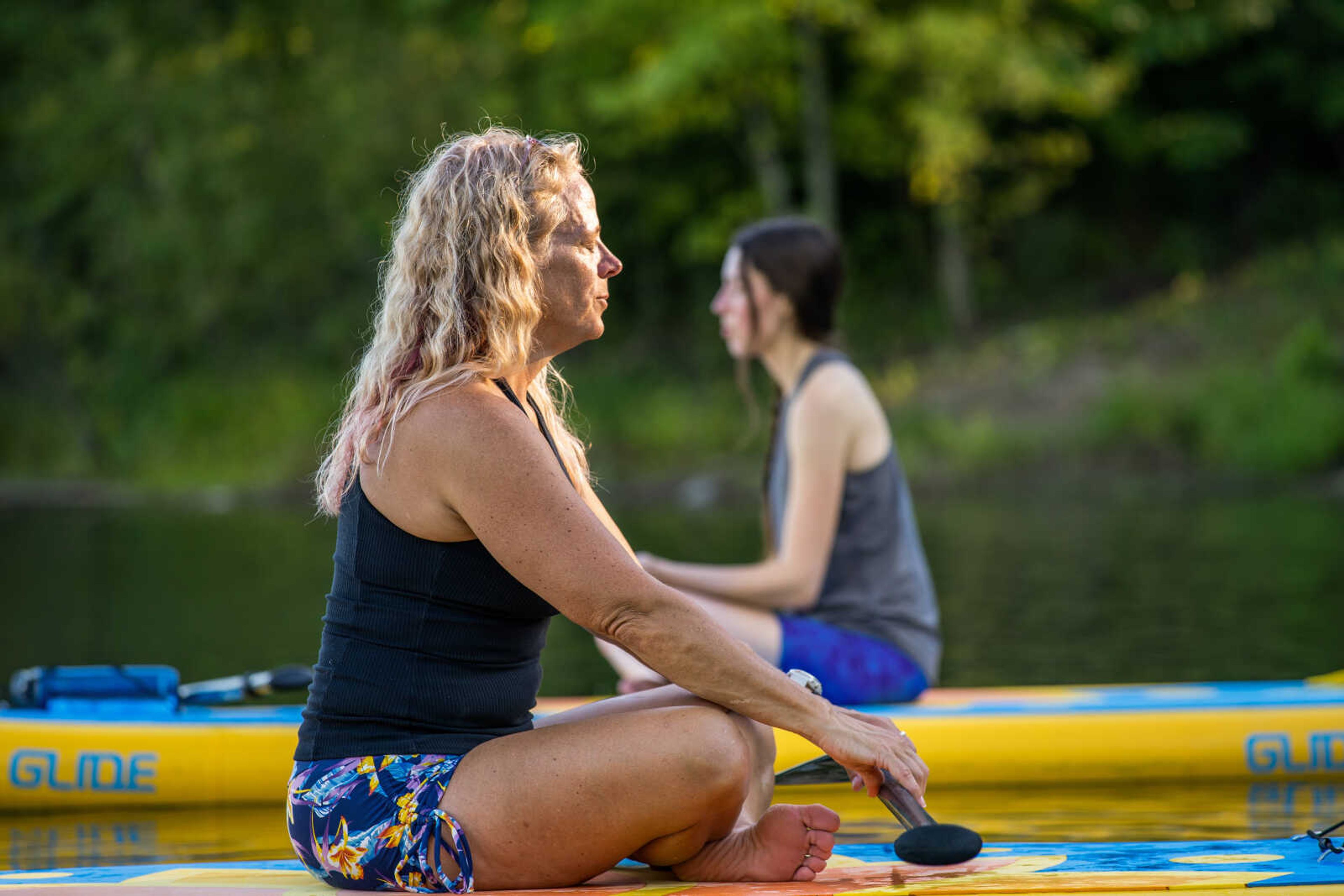 Instructor Missy Nieveen Phegley leads her SUP yoga class in a guided mindfulness exercise. Practicing SUP yoga helps students improve their yoga on land.