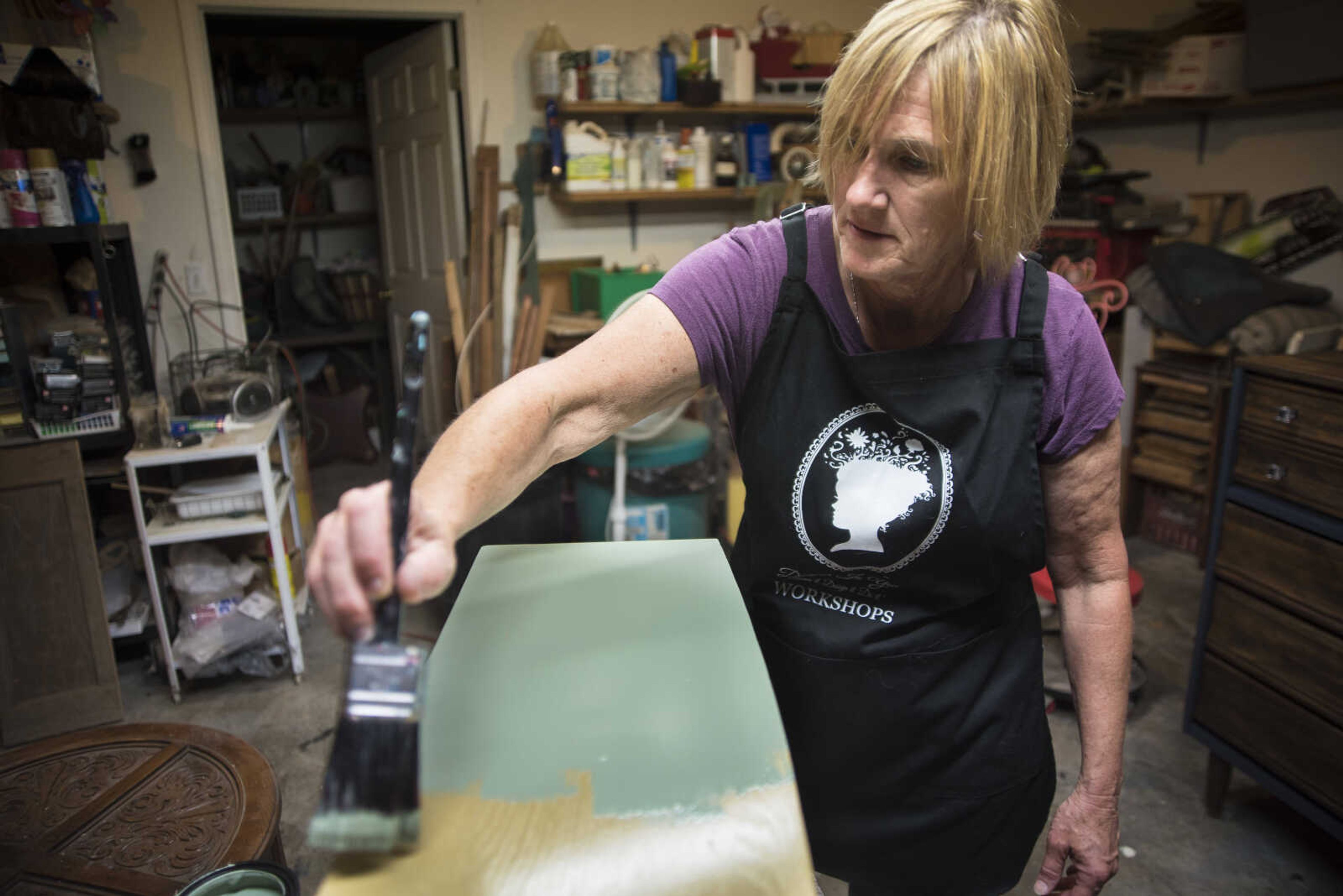 Debbie Birk paints the front of a drawer that she is fixing up in her garage Wednesday, July 26, 2017 in Jackson