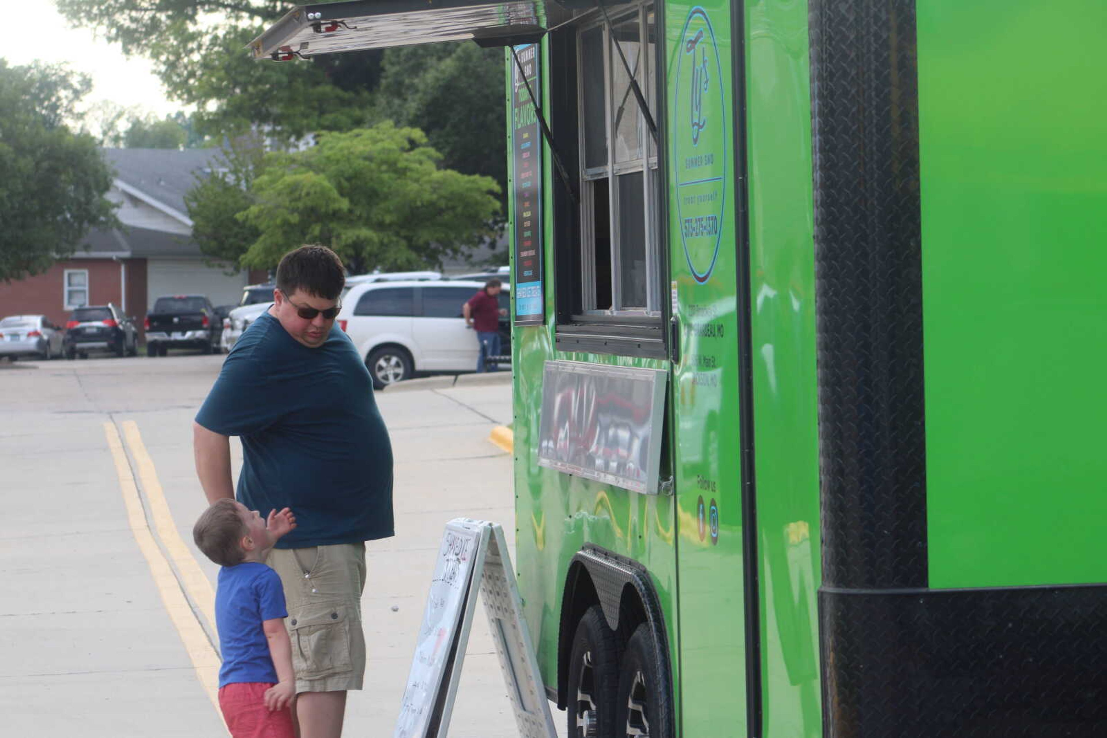 A father and son wait for shaved ice at the TyвЂ™s Summer Sno food truck during the Cape Broadway Theatre Festival on Saturday, July 18, 2021, in the parking lot on the northeast corner of Broadway and Pacific Street in Cape Girardeau.