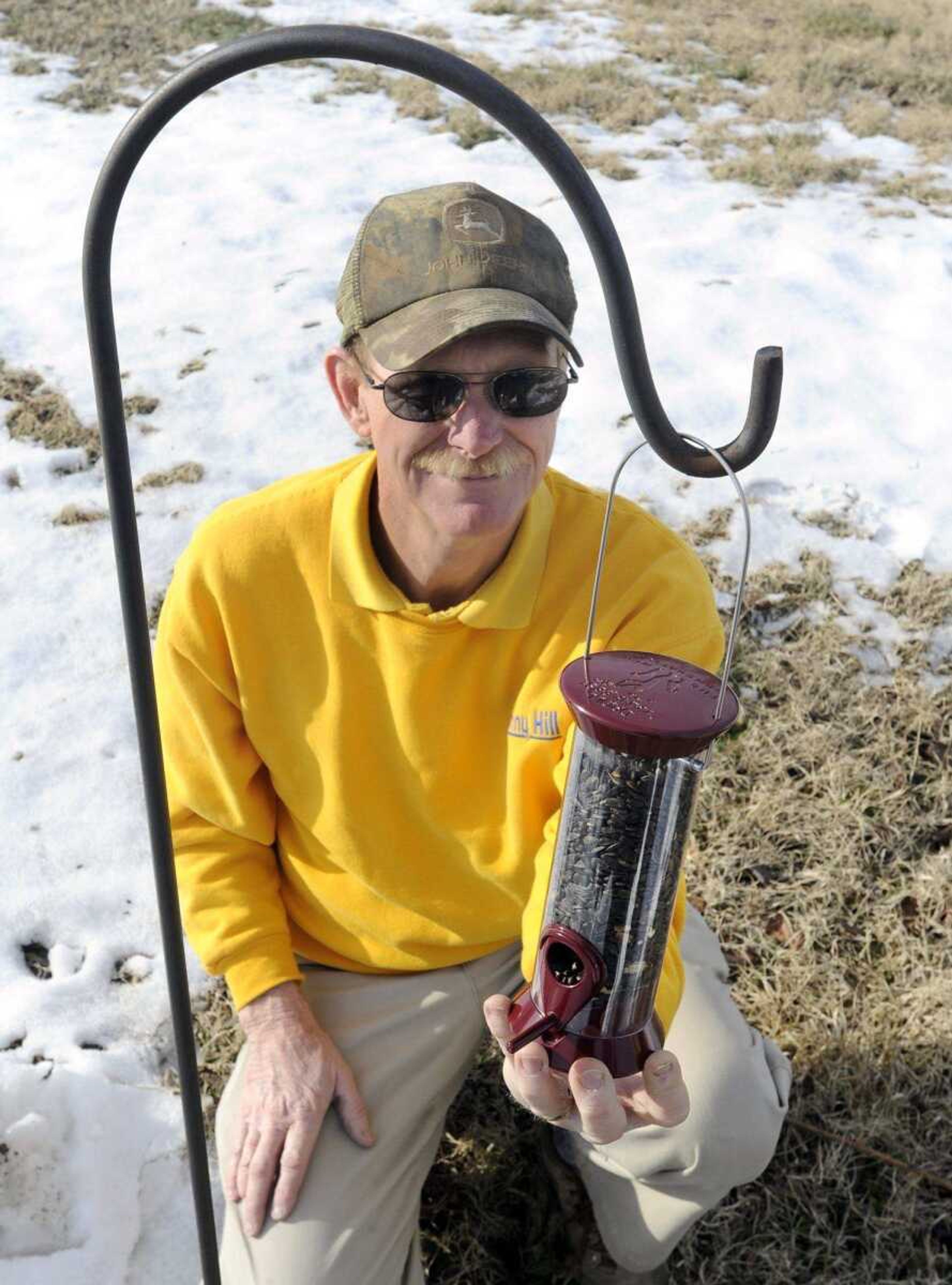 Leroy Schenimann shows a tube feeder filled with black oil sunflower seeds that birds can find on a shepherd&#8217;s hook. (Fred Lynch)