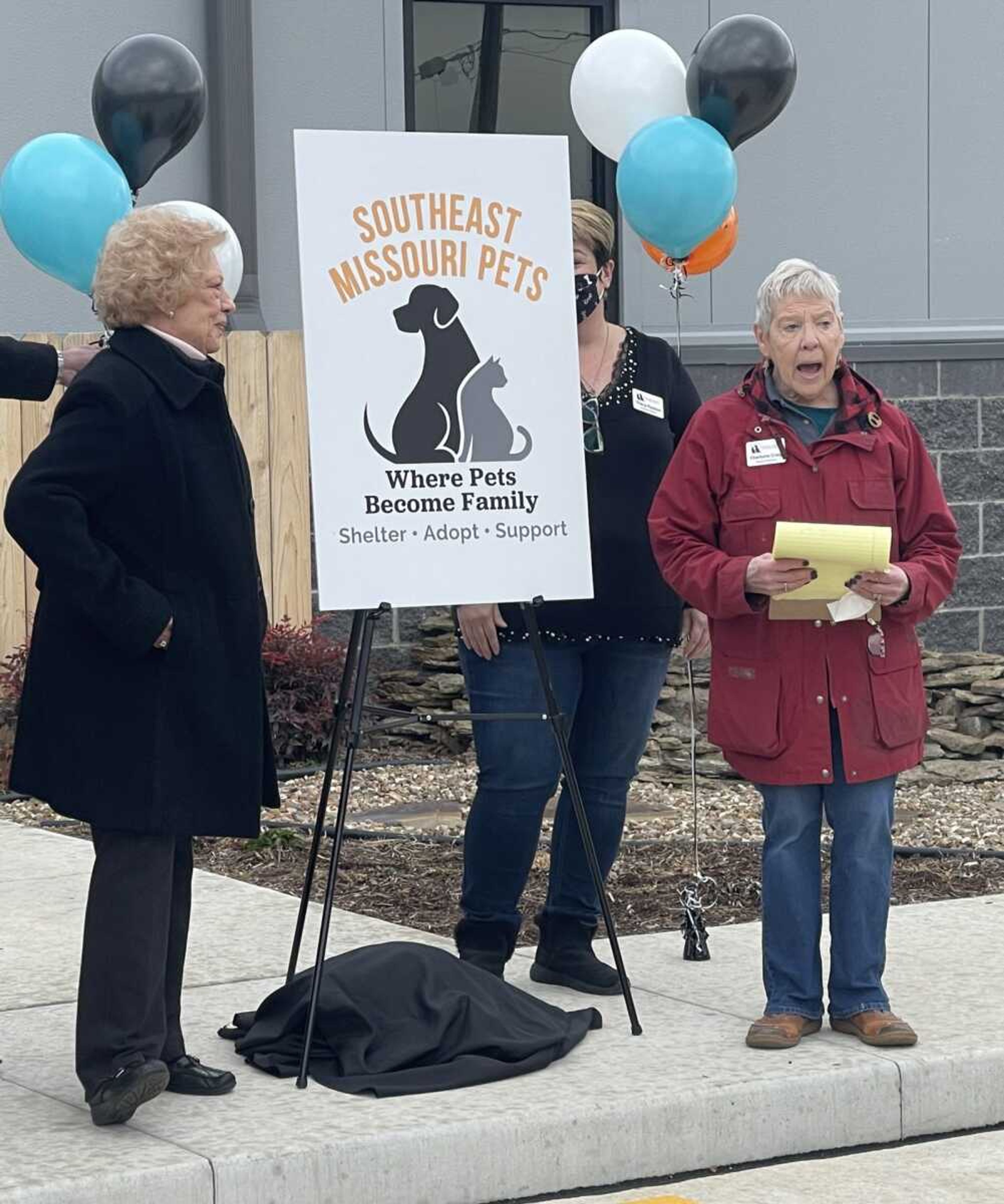 Charlotte Craig, right, president of the Southeast Missouri Pets board, and board member Karen Honaas unveil the new name and logo of the organization formerly known as Humane Society of Southeast Missouri. Partially obscured by the sign is Tracy Poston, the organization's executive director. Board members and patrons held a ribbon-cutting ceremony Thursday at the group's new 12,000-square-foot facility