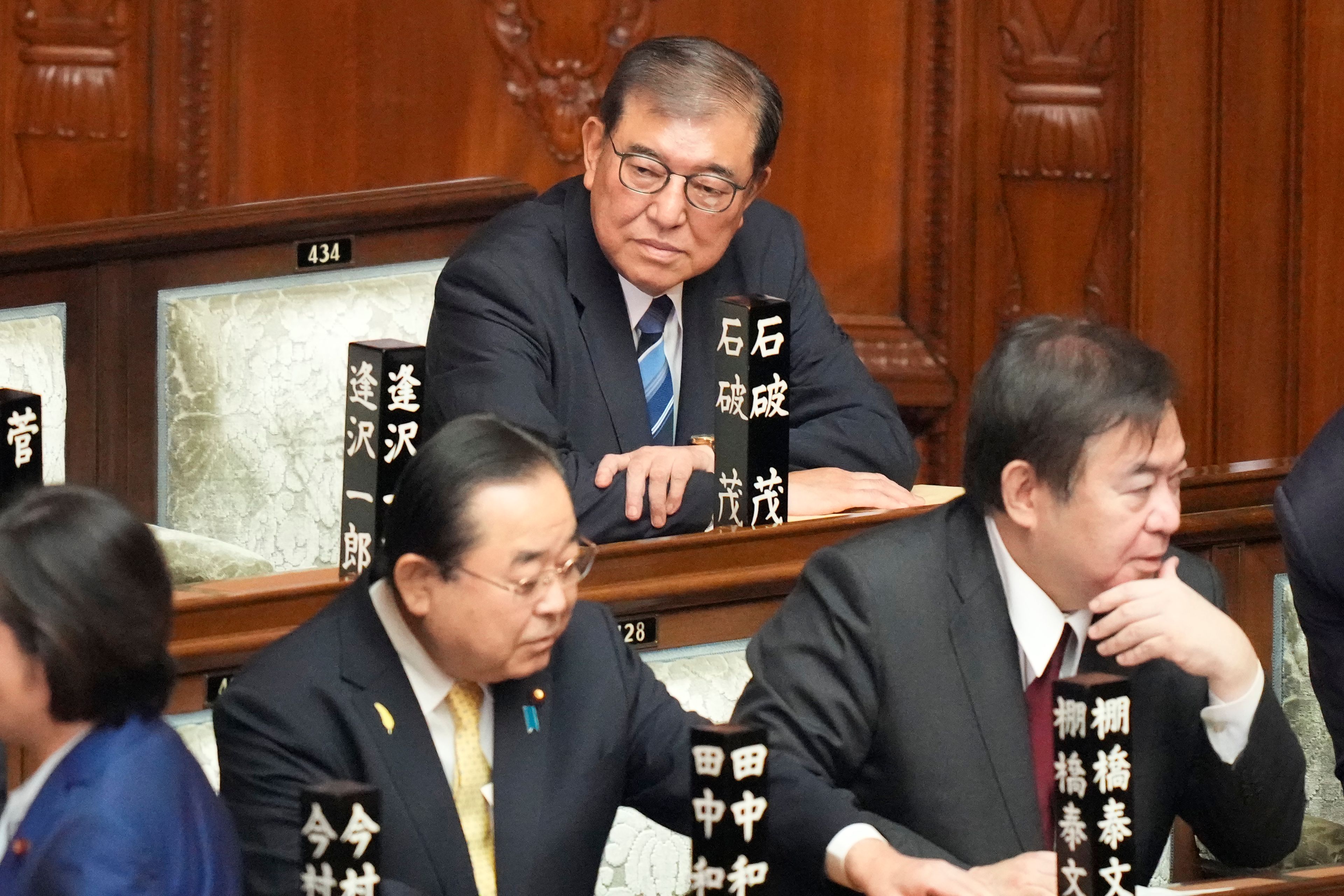 Shigeru Ishiba, top, sits ahead of the extraordinary session of parliament's lower house Tuesday, Oct. 1, 2024, in Tokyo. (AP Photo/Eugene Hoshiko)