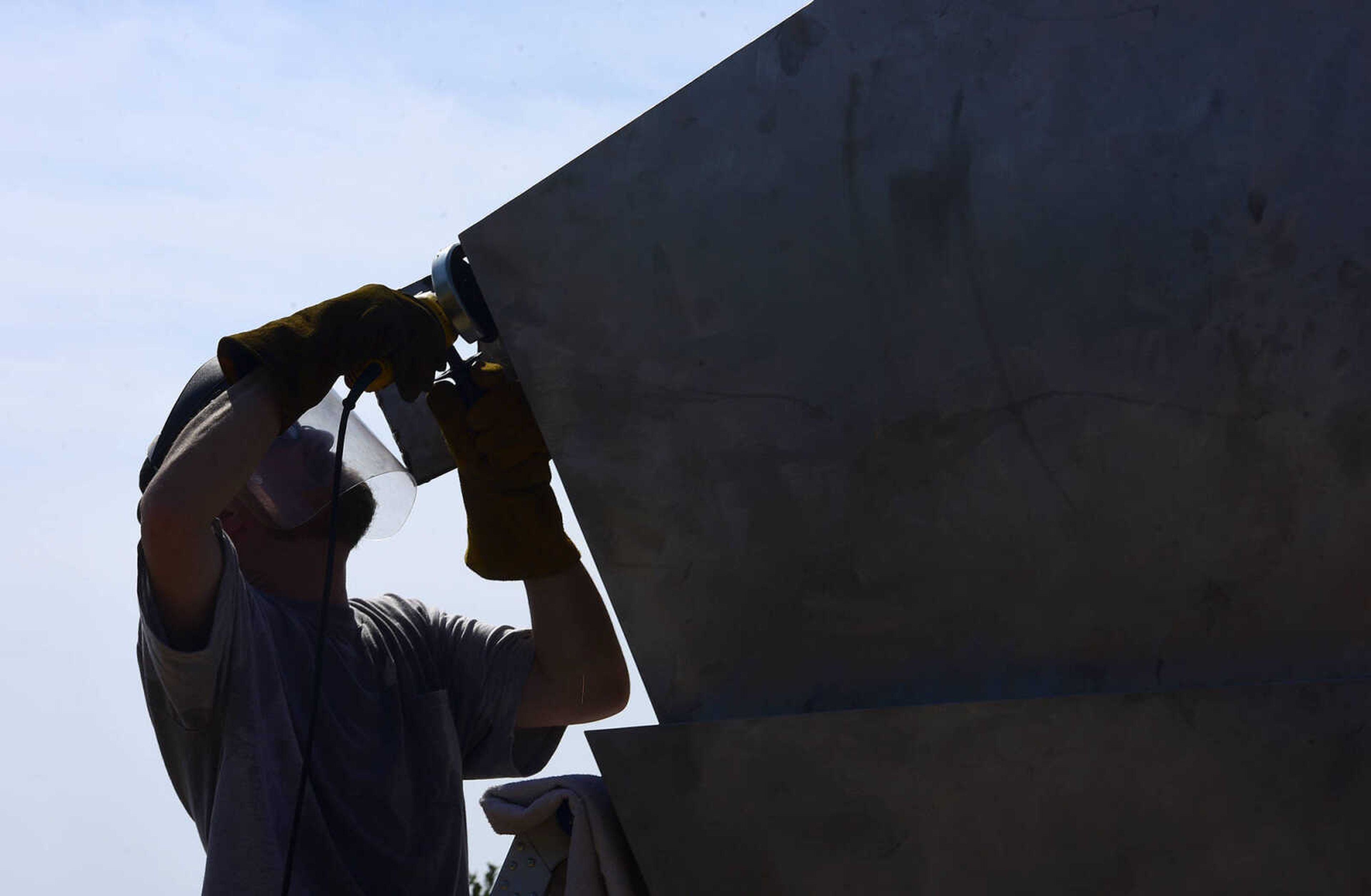 Chris Wubbena cuts an eyelet off of his sculpture, "Commence" that was used to help install the two-piece 14-foot sculpture in the Fountain Street roundabout on Monday, July 24, 2017, near the River Campus in Cape Girardeau.