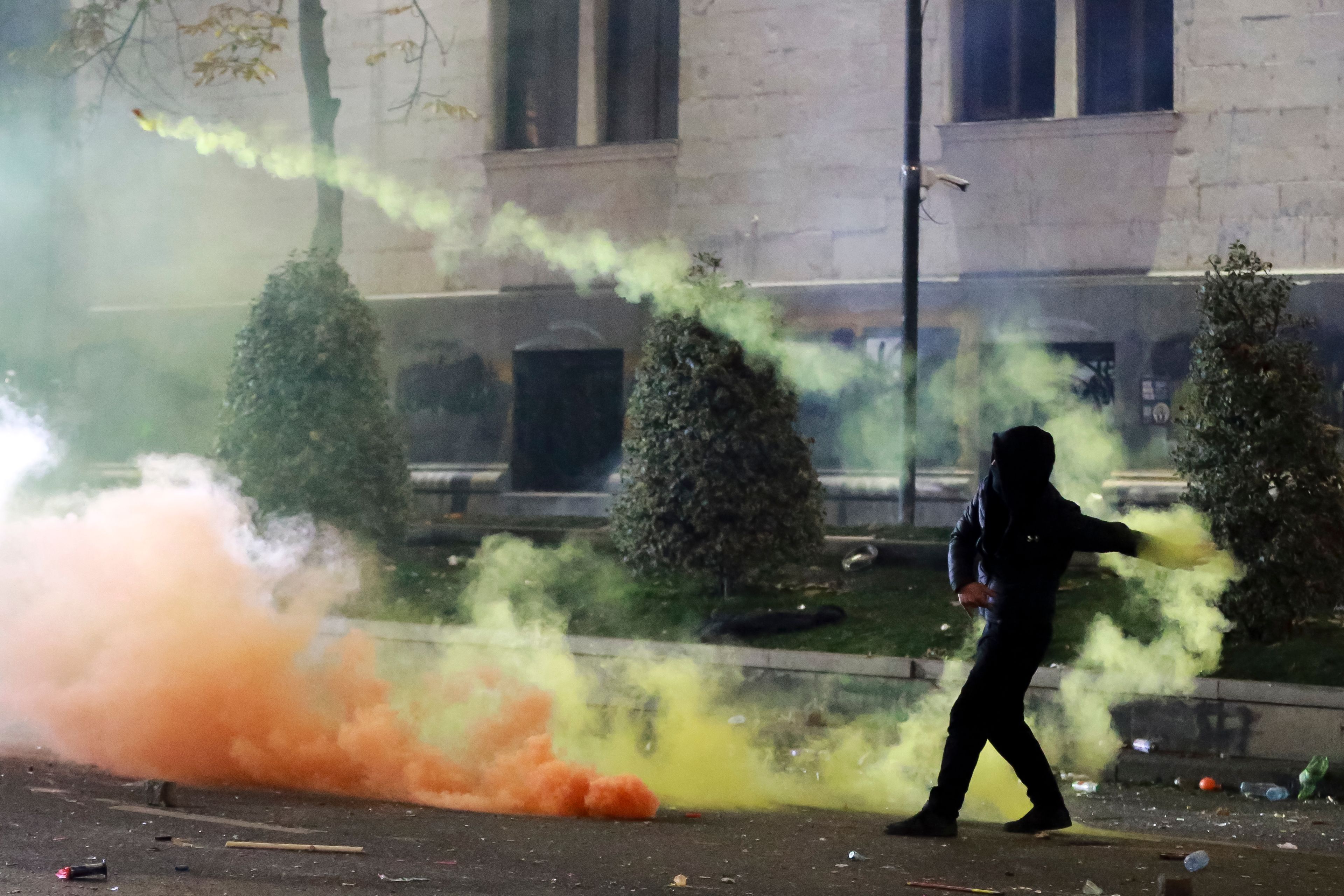 A demonstrator throws a firecracker toward police as police block a street to prevent protesters rallying against the government's decision to suspend negotiations on joining the European Union for four years, outside the parliament's building in Tbilisi, Georgia, early Saturday, Nov. 30, 2024. (AP Photo/Zurab Tsertsvadze)