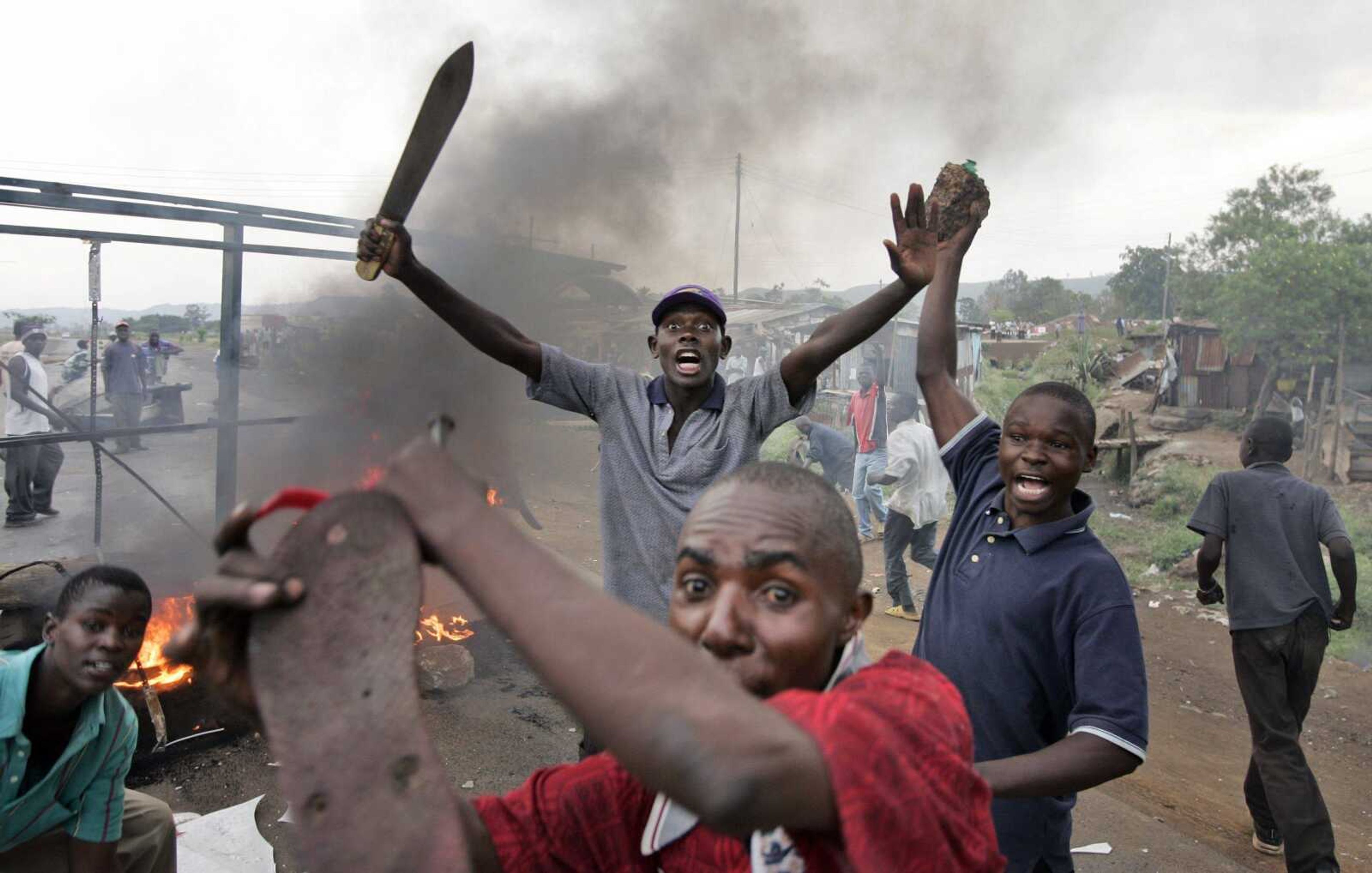 Kenyan men from the Luo tribe armed with machetes and rocks enforced a makeshift roadblock Monday, searching passing vehicles for Kikuyus trying to flee the town in order to kill them, on the main road to the Ugandan border near the airport in Kisumu. (BEN CURTIS ~ Associated Press)