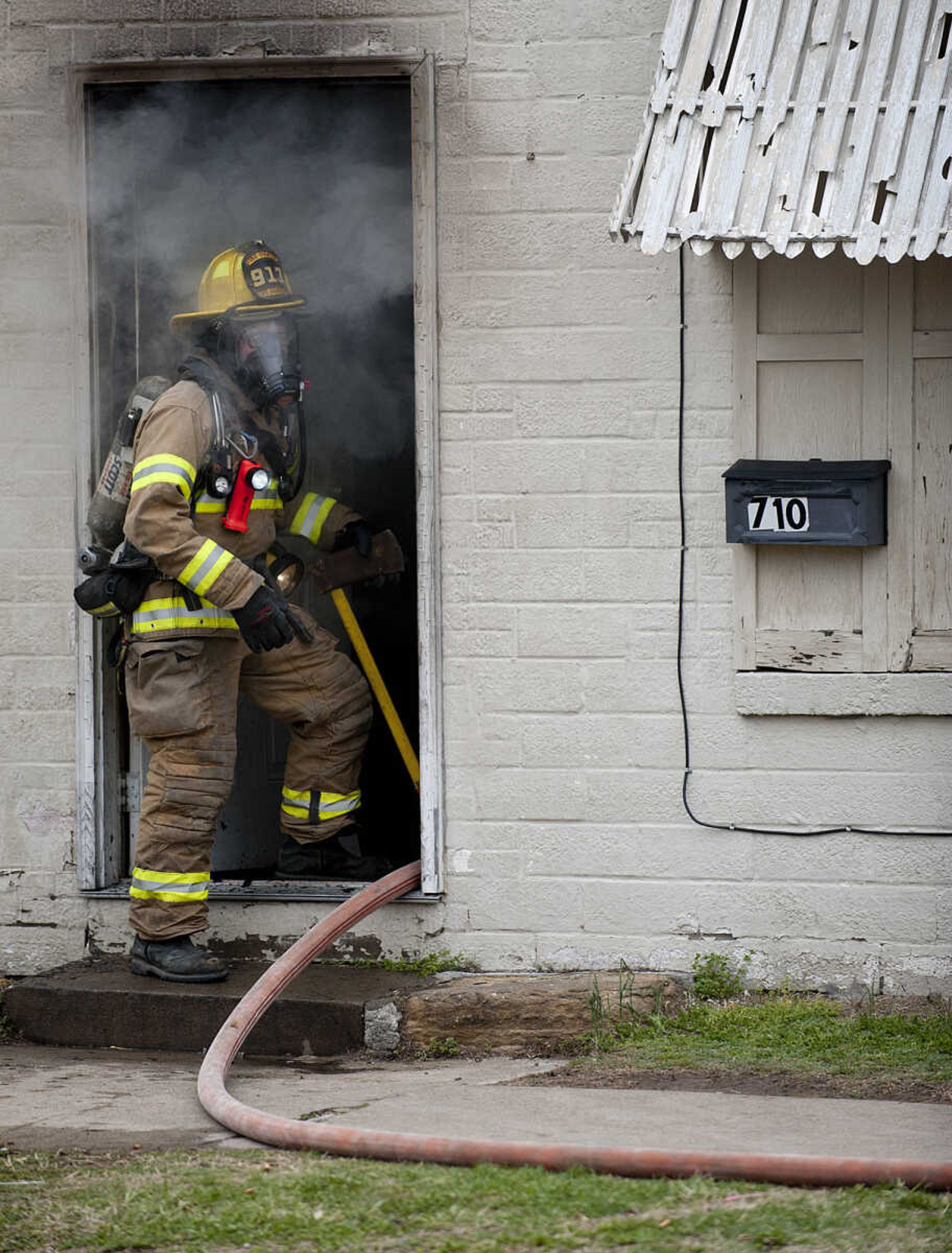 A firefighter walks in the door of a building at 710 Morgan Oak St., as the Cape Girardeau battle battle a structure fire Tuesday, April 29, in Cape Girardeau. A Cape Girardeau Police officer saw the fire and called it in at 1:16 p.m. The building contained two apartments that were home to five people, though no one was home at the time of the fire. The cause of the fire is under investigation.