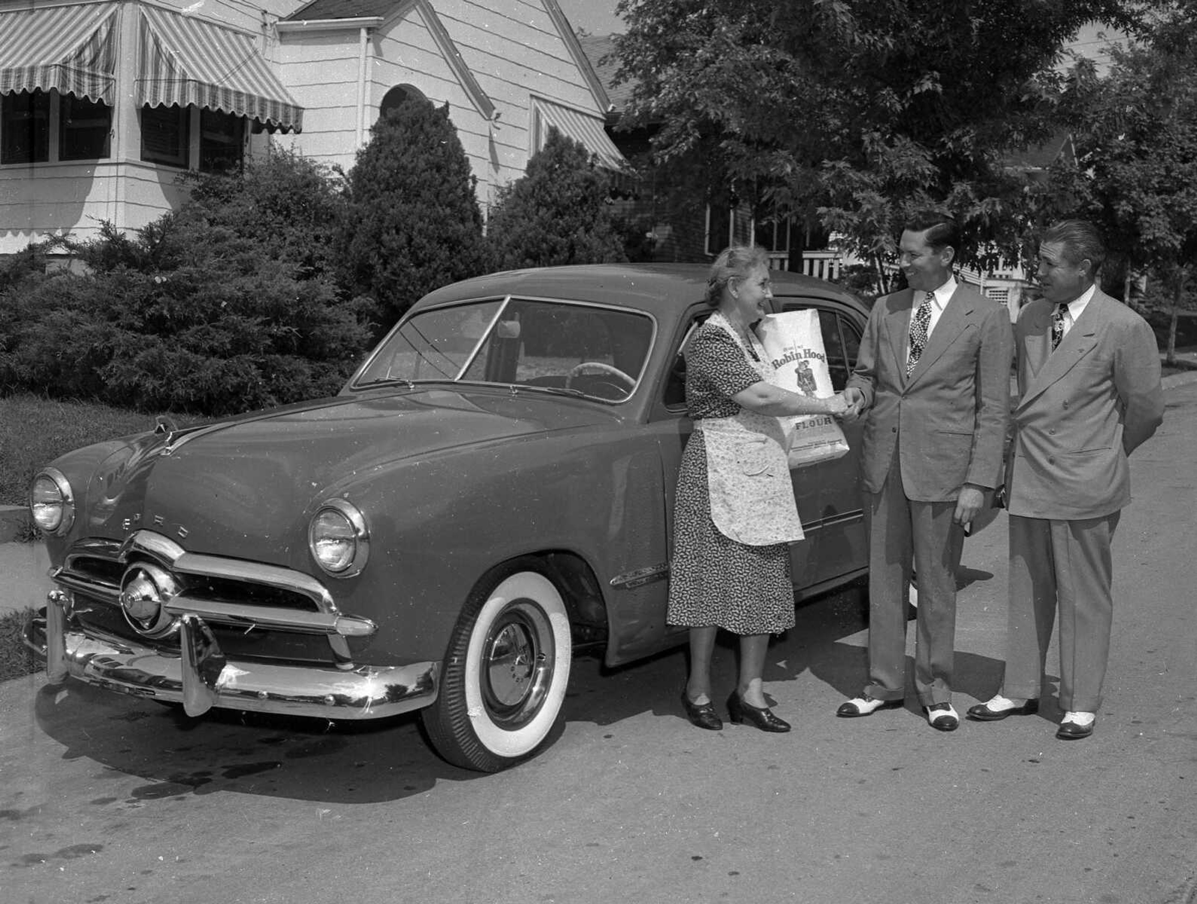 Aug. 7, 1948 Southeast Missourian.
Mrs. Charles Poe, 1431 Rose Street, is receiving congratulations from Robert C. Evans, sales manager for Groves Motor Co., for winning the new Ford automobile shown behind her, in a national contest to name a new roll recipe. With Mr. Evans is D.A. Mahaffey of St. Louis, division sales manager for the Robin Hood Flour Co., sponsors of the contest, who made the presentation. (G.D. Fronabarger/Southeast Missourian archive)