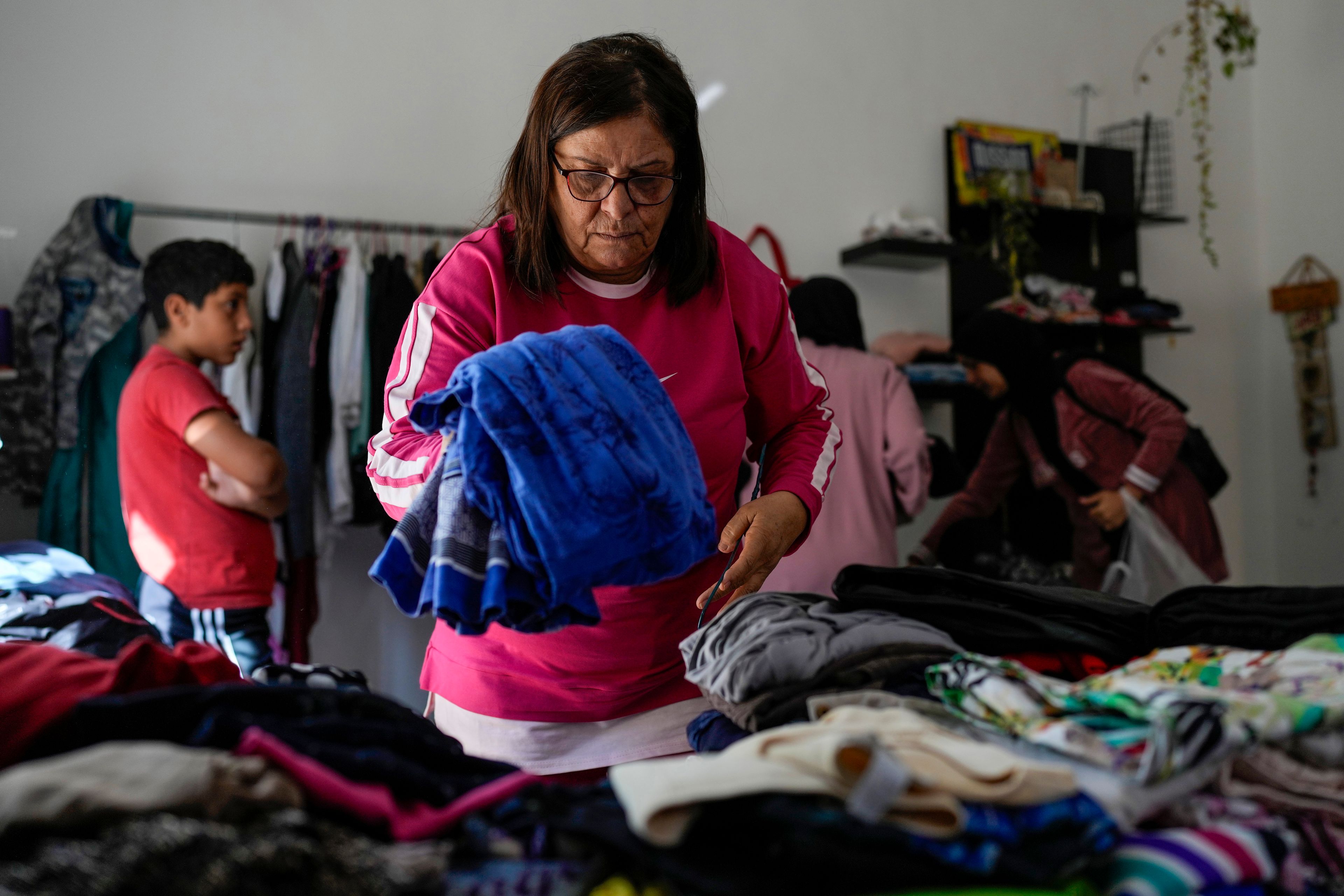 Displaced people select winter clothes at a women's art center that has turned into a kitchen for displaced people who fled southern Lebanon amid the ongoing Hezbollah-Israel war, in the town of Aqaibe, northern Lebanon, Thursday, Oct. 24, 2024. (AP Photo/Hassan Ammar)