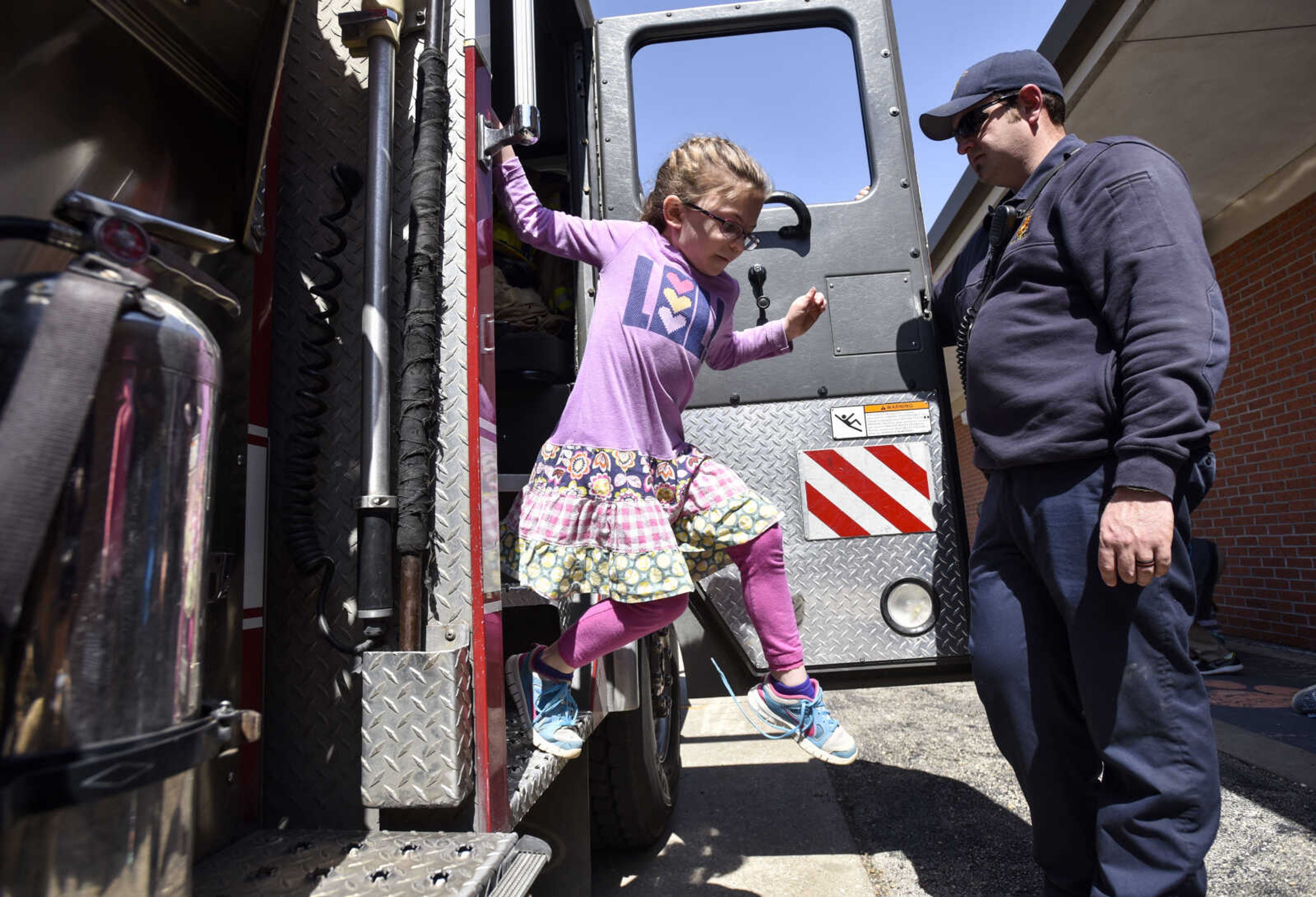 Cape Girardeau firefighter Justin Siemers holds the door for a second grade student at Alma Schrader elementary as she jumps out of a firetruck Tuesday, April 17, 2018, in Cape Girardeau.