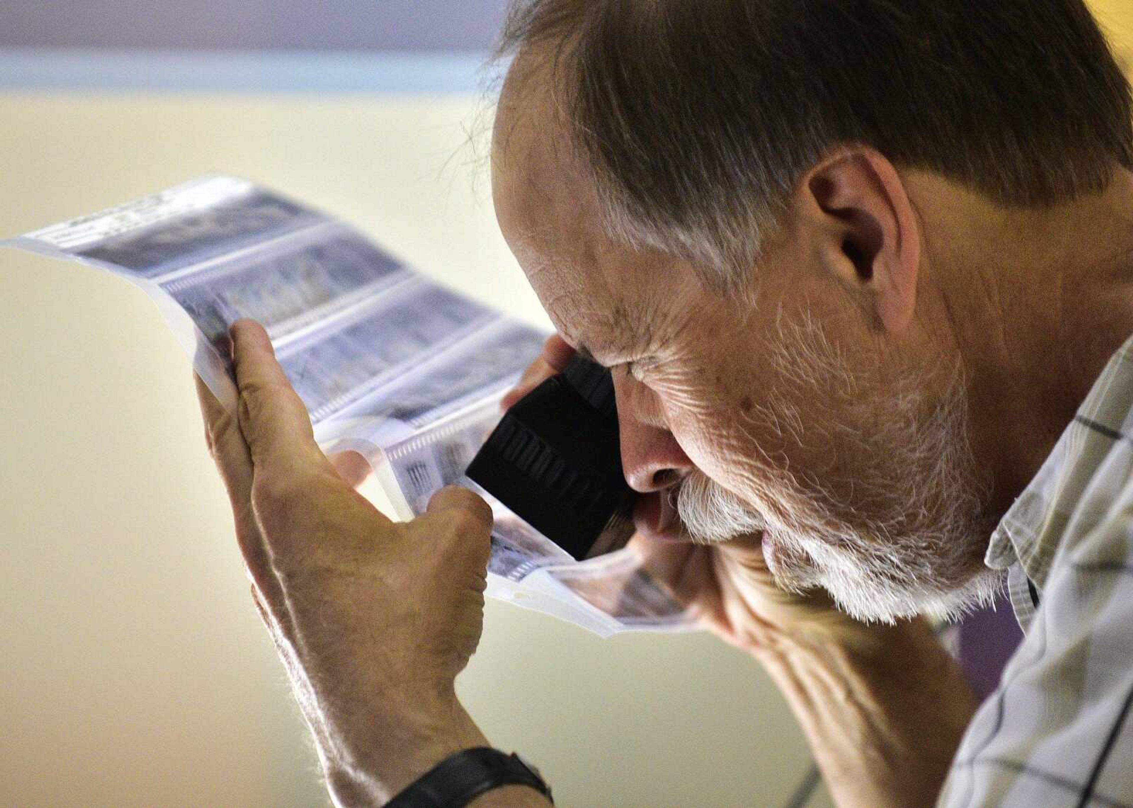 Southeast Missourian photojournalist, Fred Lynch, looks through a sleeve of old black-and-white negatives in the photo office on Friday, June 9.