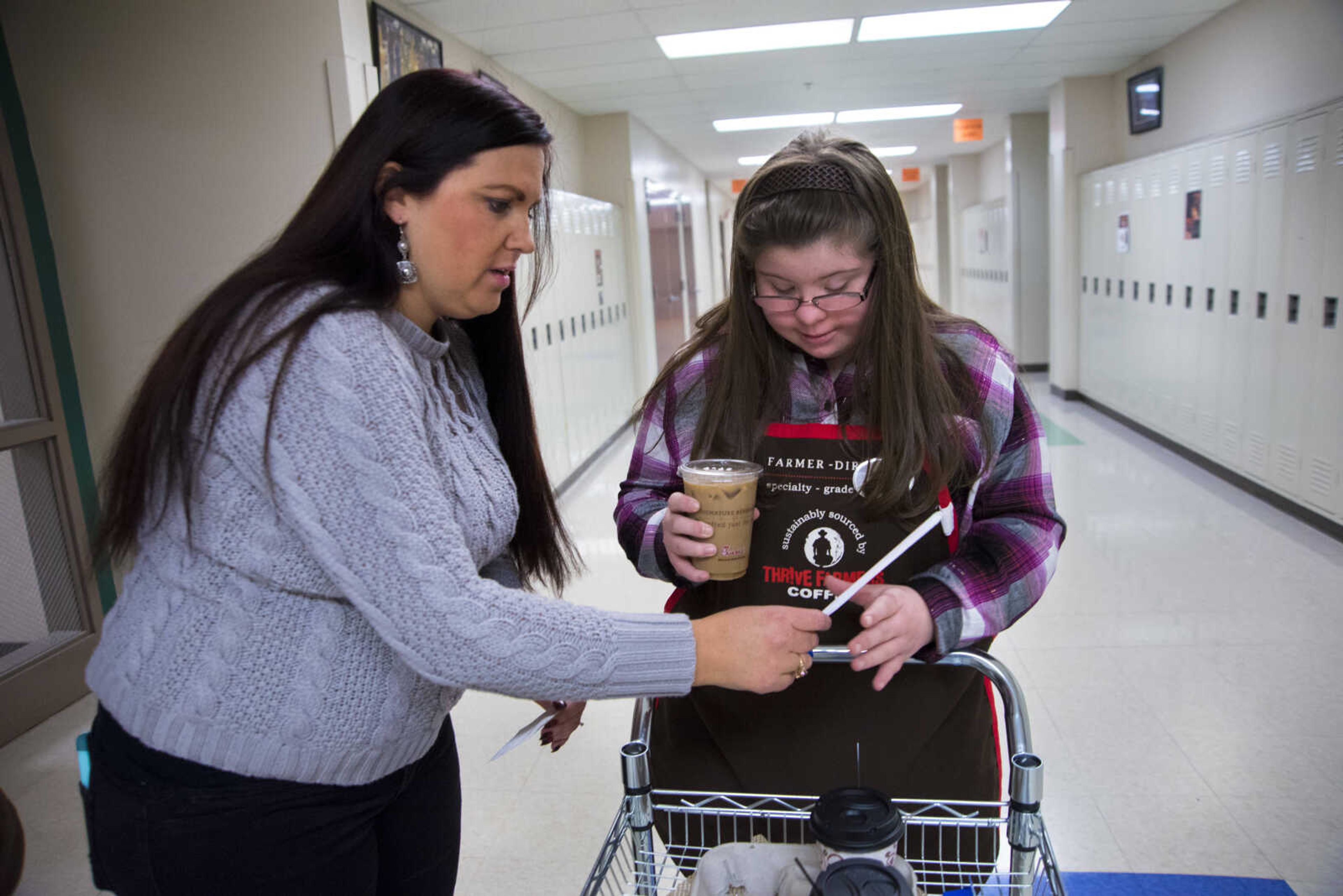 ANDREW J. WHITAKER ~ awhitaker@semissourian.com
Sara Taylor-Umfleet, left, and Cori Brennecke, right, grab an iced coffee off a cart for Tiger Brew, a student run business run by the special education department at Cape Girardeau Central, Tuesday, Dec. 13, 2016 in Cape Girardeau. Tiger Brew is available Monday through Friday during three different class periods, 1st hour, 2nd hour and advisory and offer a variety of drinks from hot coffees and teas, iced drinks, hot chocolates and even smoothies.