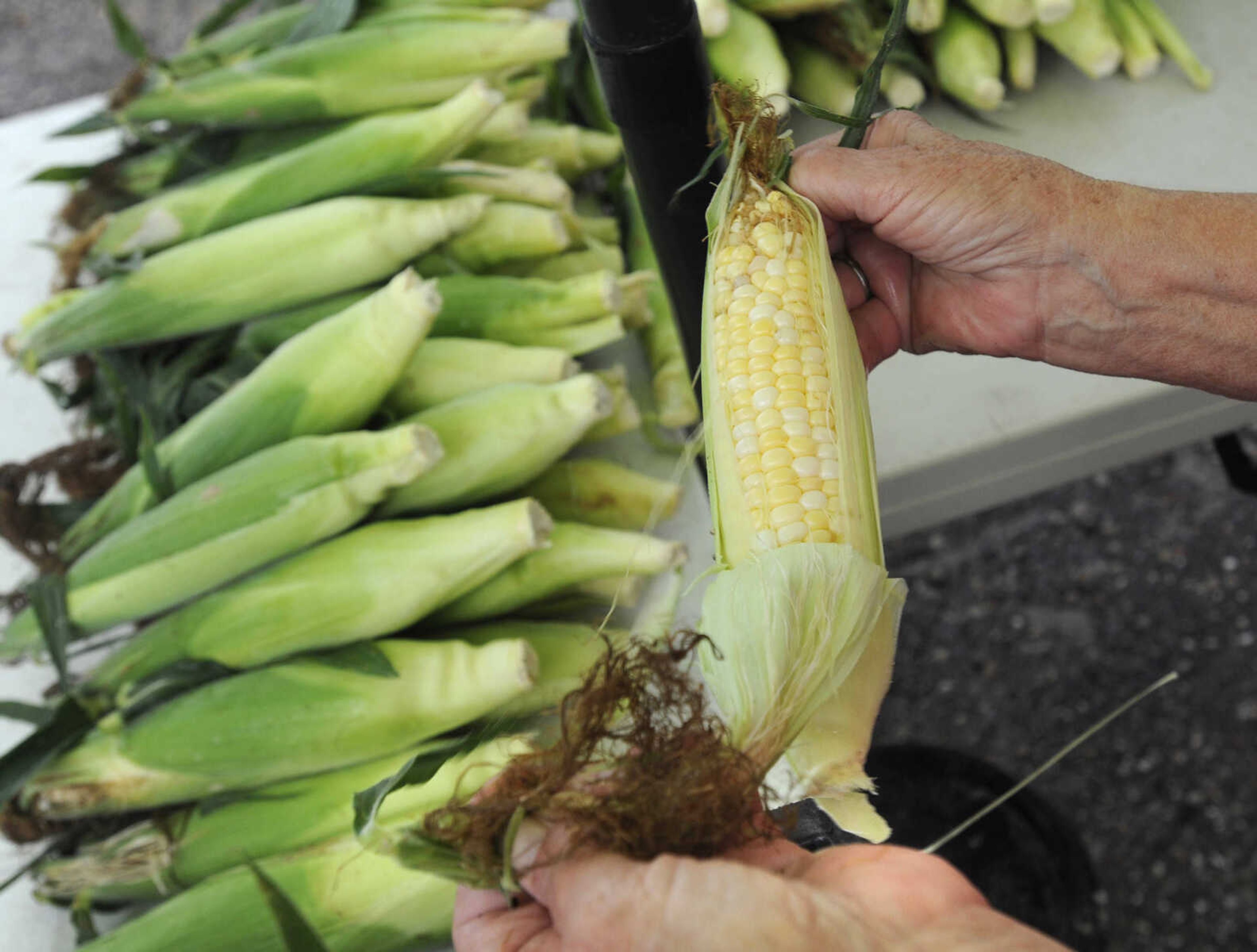 Ruth Menard opens up sweet corn to show a customer Tuesday, July 7, 2015 at the Jackson Farmer's Market in Jackson.