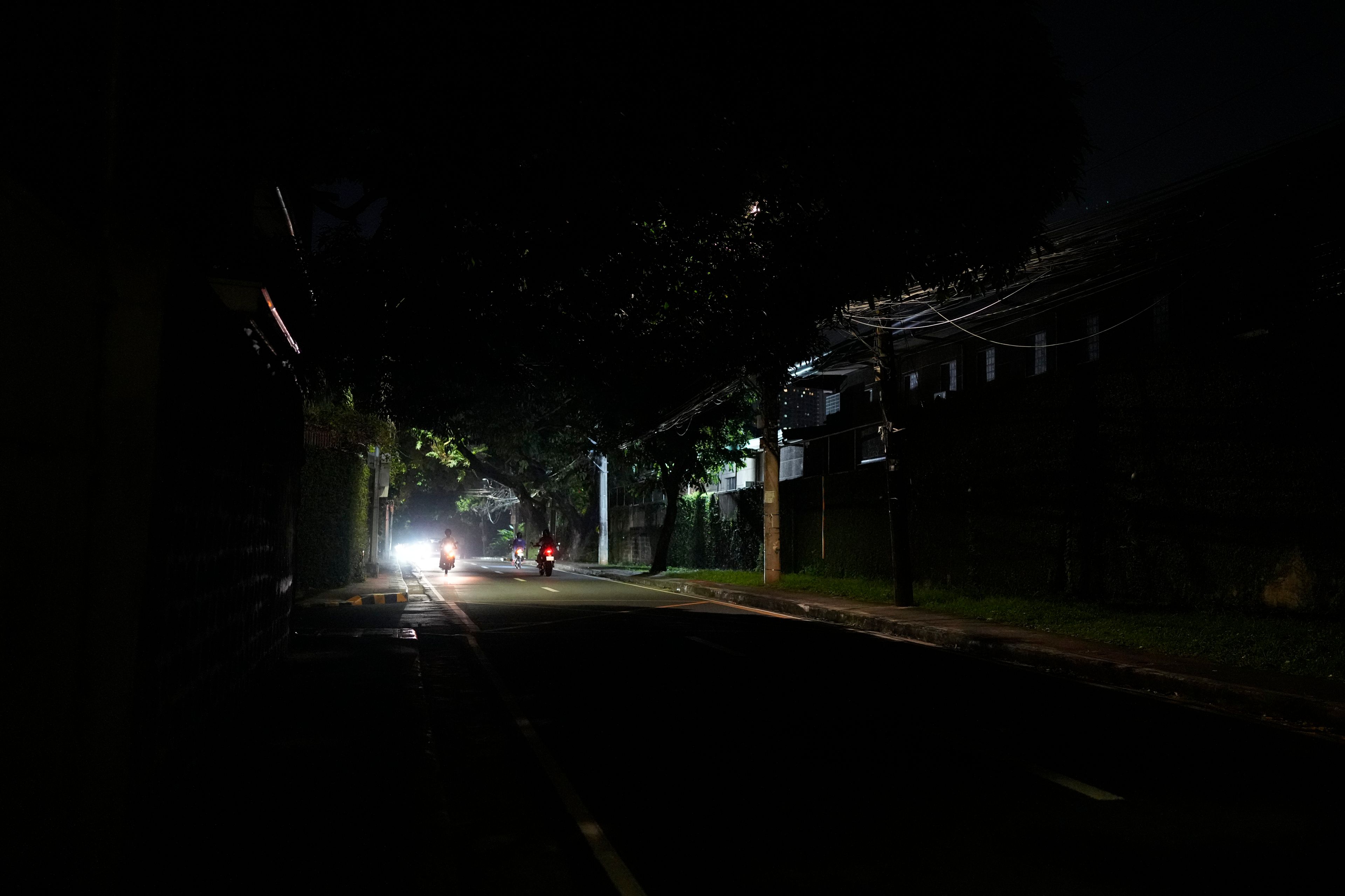 Vehicles pass by a dimly lit portion of Balete Drive in Quezon City, Philippines, Friday, Oct. 25, 2024. (AP Photo/Aaron Favila)