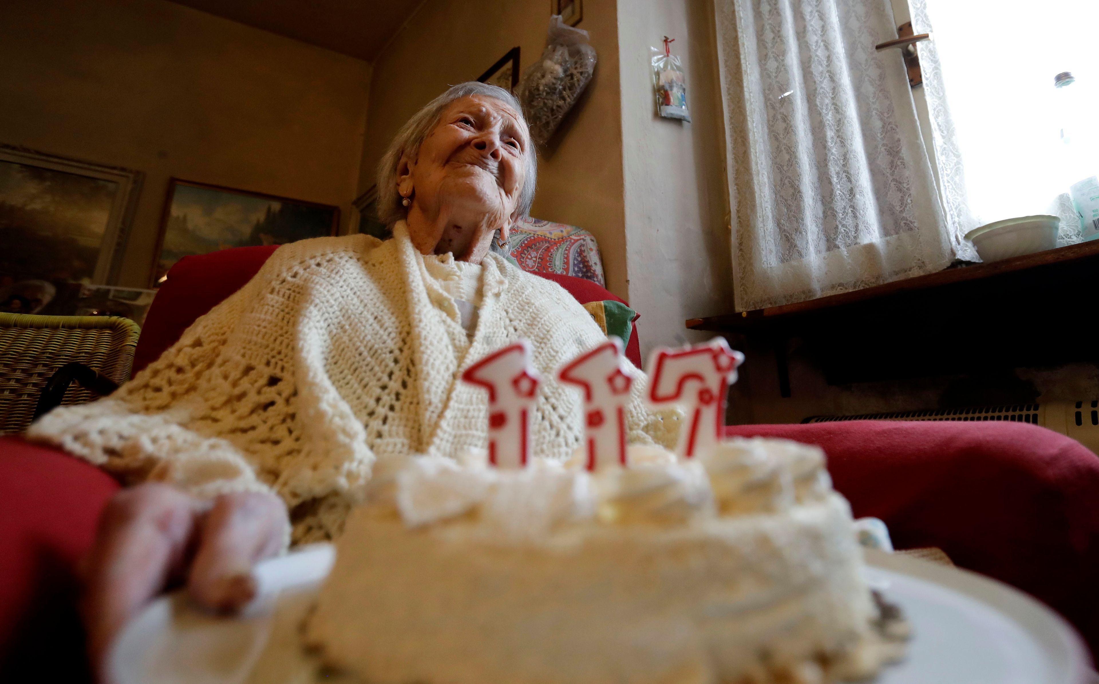 FILE- Emma Morano holds a cake with candles marking 117 years on the day of her birthday, Nov. 29, 2016, in Verbania, Italy. (AP Photo/Antonio Calanni)