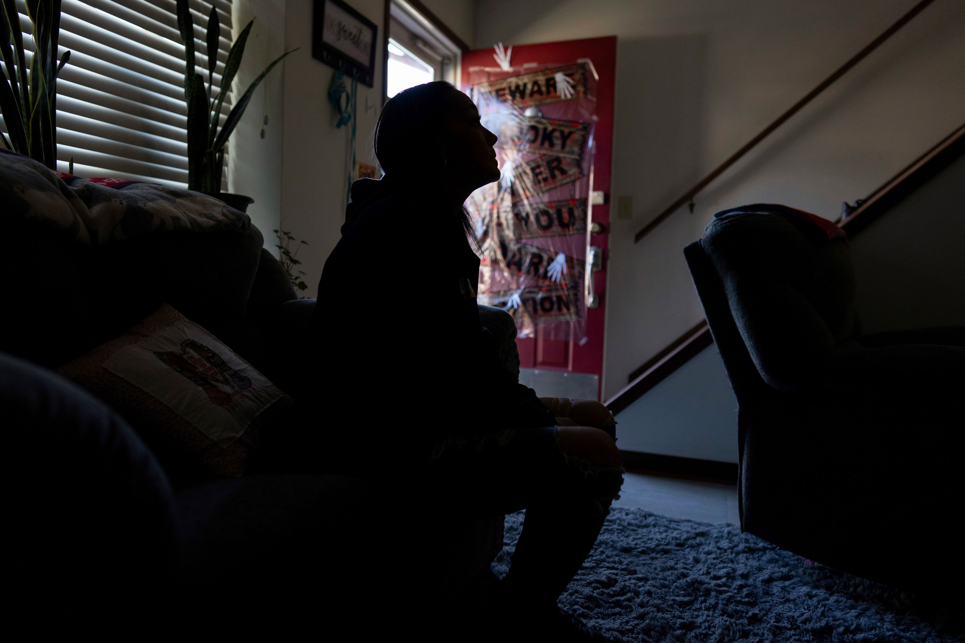 April Youst is silhouetted as she sits on her living room sofa in West Virginia on Wednesday, Oct. 9, 2024. (AP Photo/Carolyn Kaster)