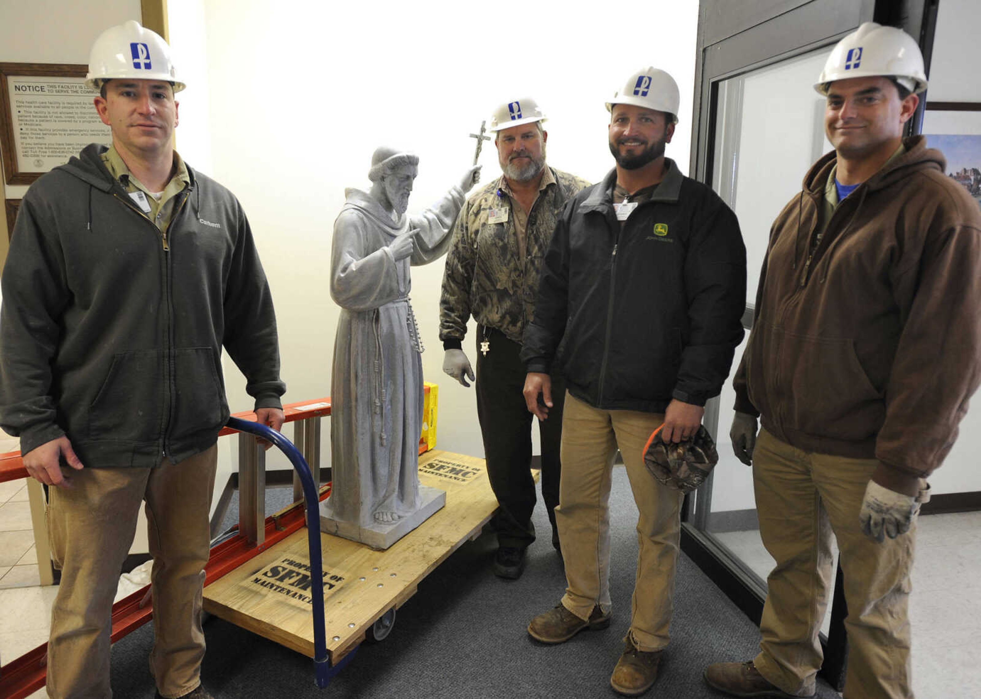 Matt Underwood, left, Greg Holshouser, Shawn Roll-Huston and Nathan Bahr pose Wednesday, Nov. 28, 2012 with the statue of St. Francis of Assisi which they removed from the fountain at Saint Francis Medical Center after a groundbreaking ceremony.