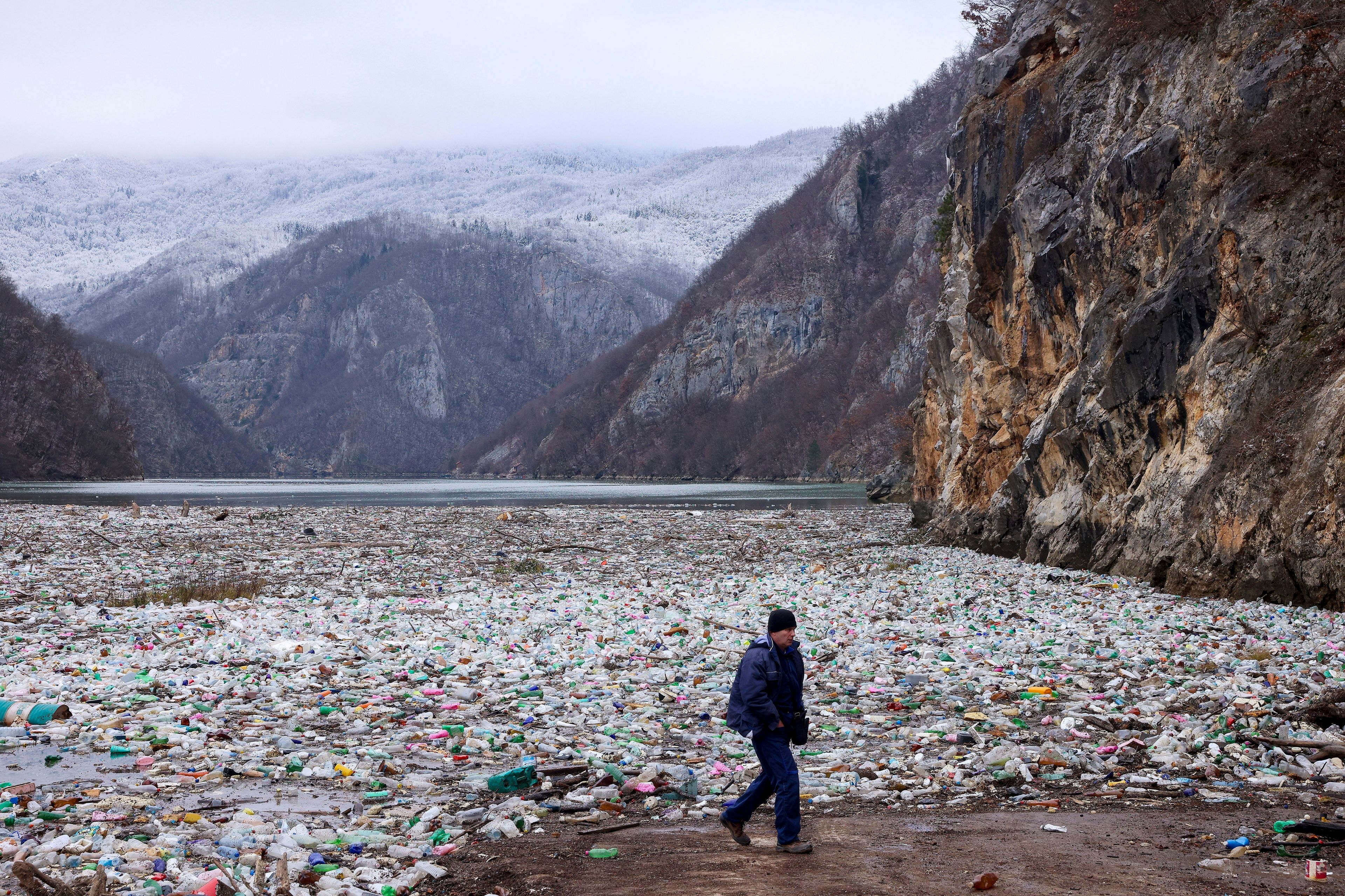 FILE- A man walks past waste floating in the Drina river near Visegrad, Bosnia, Jan. 10, 2024. (AP Photo/Armin Durgut, File)