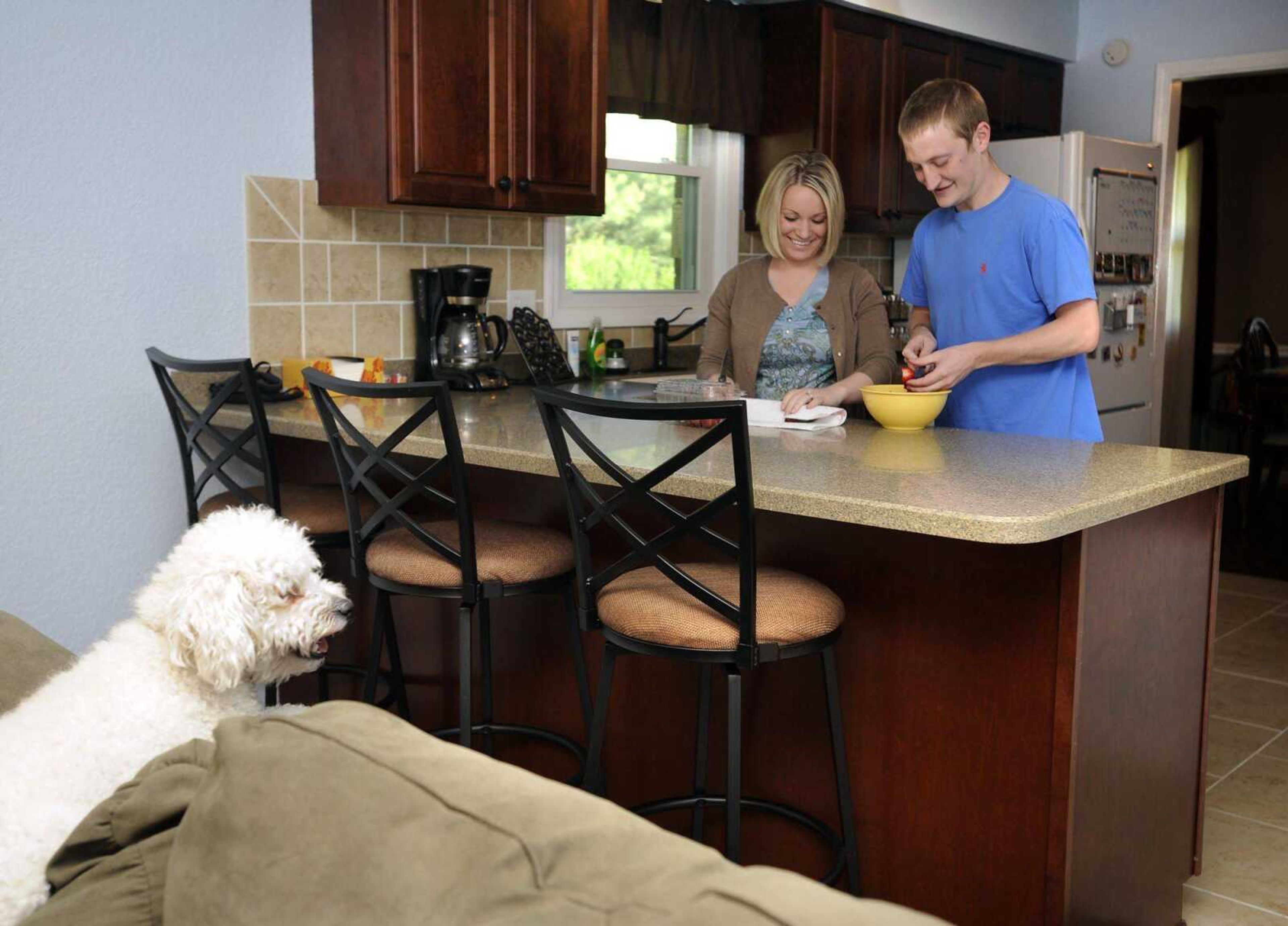 Kyle and Jenny Schade cut strawberries in the kitchen of their new home as their maltipoo, Benny, observes Wednesday, April 18, 2012 in Cape Girardeau. (Fred Lynch)