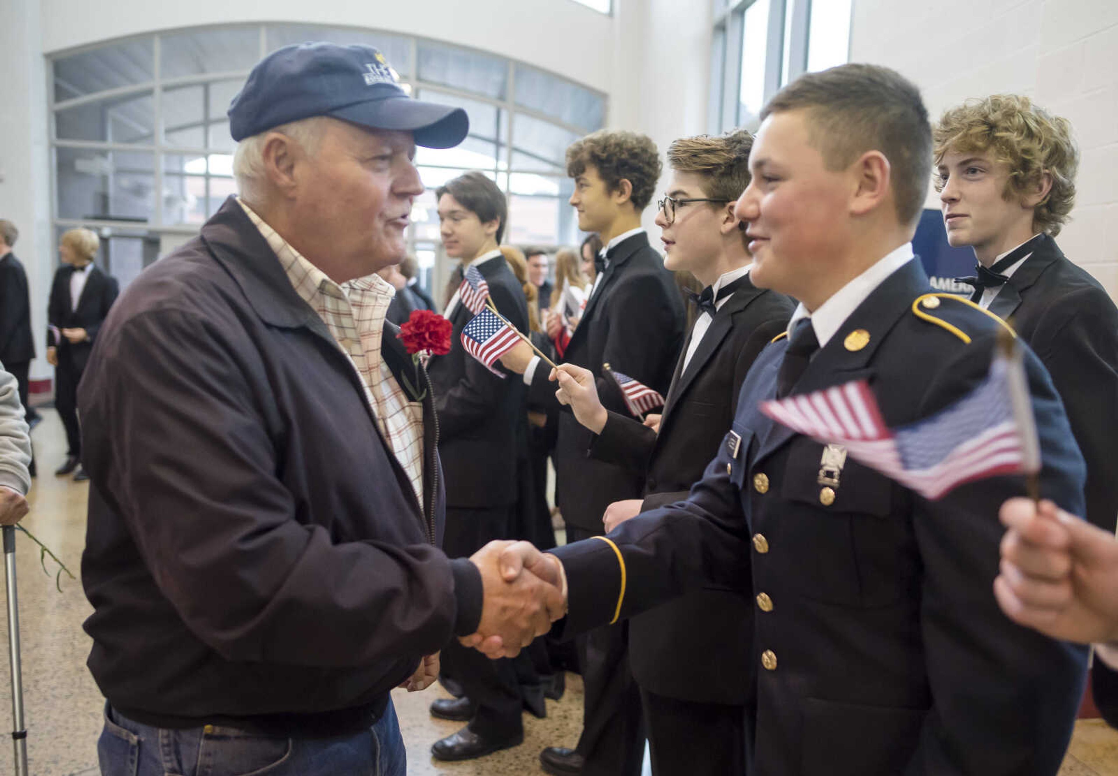 Vietnam veteran Tom Schildt, left, shakes hands with Jackson High School senior Caleb Anderson, right, during a social event in the school cafeteria after an assembly to honor veterans Monday, Nov. 11, 2019, in Jackson.