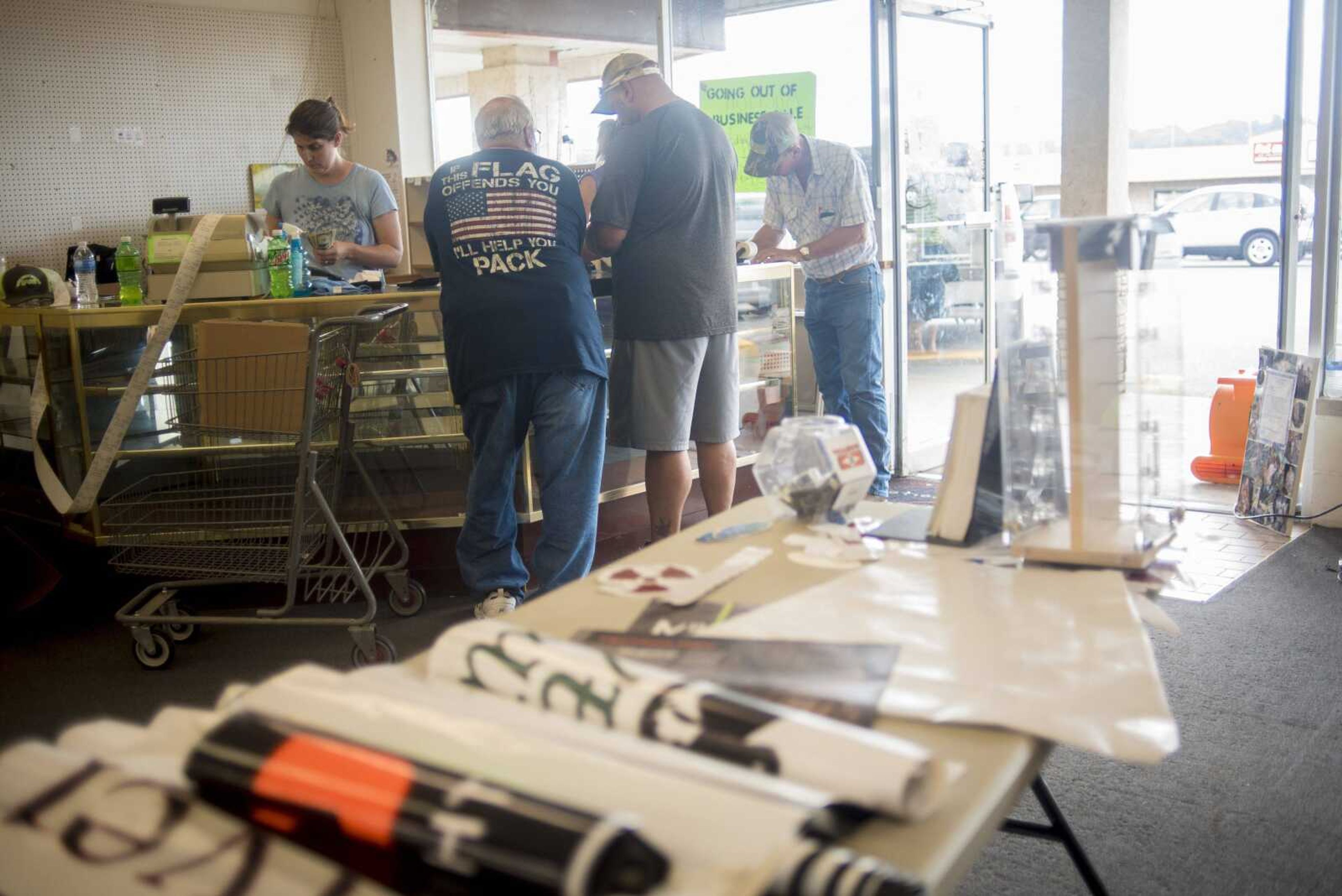 People wait in line to pay for their auctioned items from Foutz's Fishing and Hunting Shop during their closing auction Thursday in Cape Girardeau.