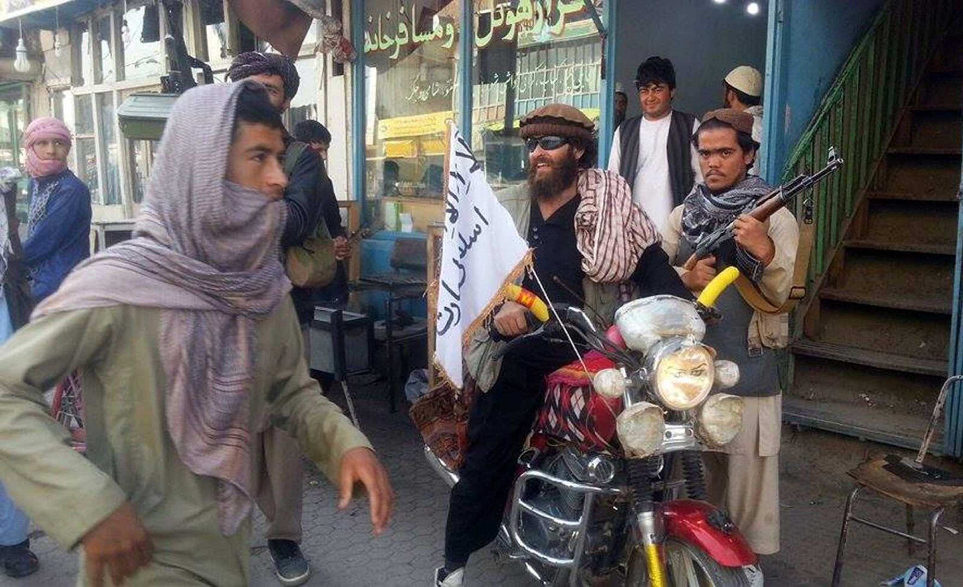 A Taliban fighter sits on his motorcycle adorned with a Taliban flag in a street Tuesday in Kunduz, Afghanistan. (Associated Press)