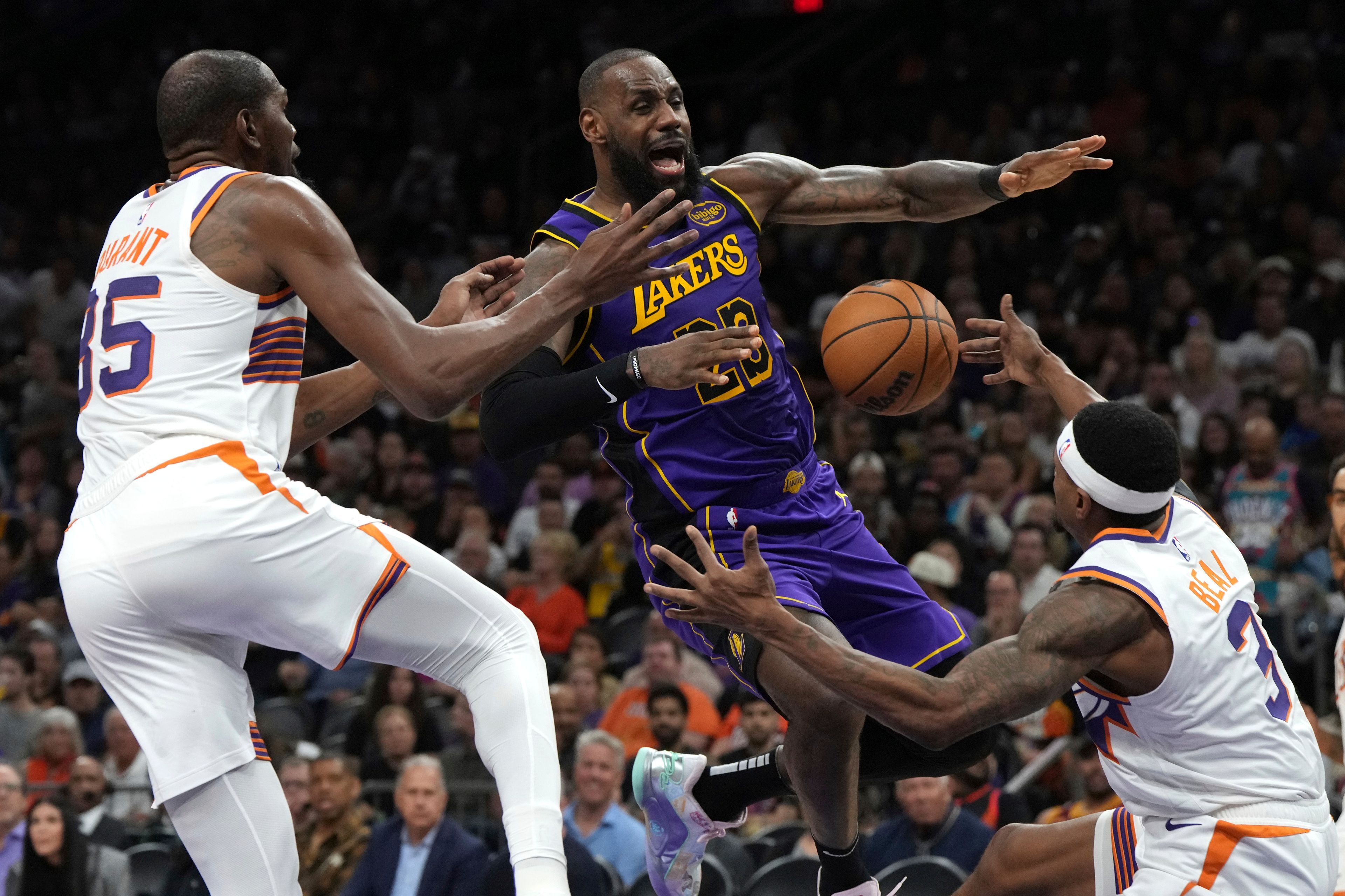 Los Angeles Lakers forward LeBron James loses the ball while driving between Phoenix Suns forward Kevin Durant and guard Bradley Beal (3) during the second half of an NBA basketball game, Monday, Oct. 28, 2024, in Phoenix. (AP Photo/Rick Scuteri)