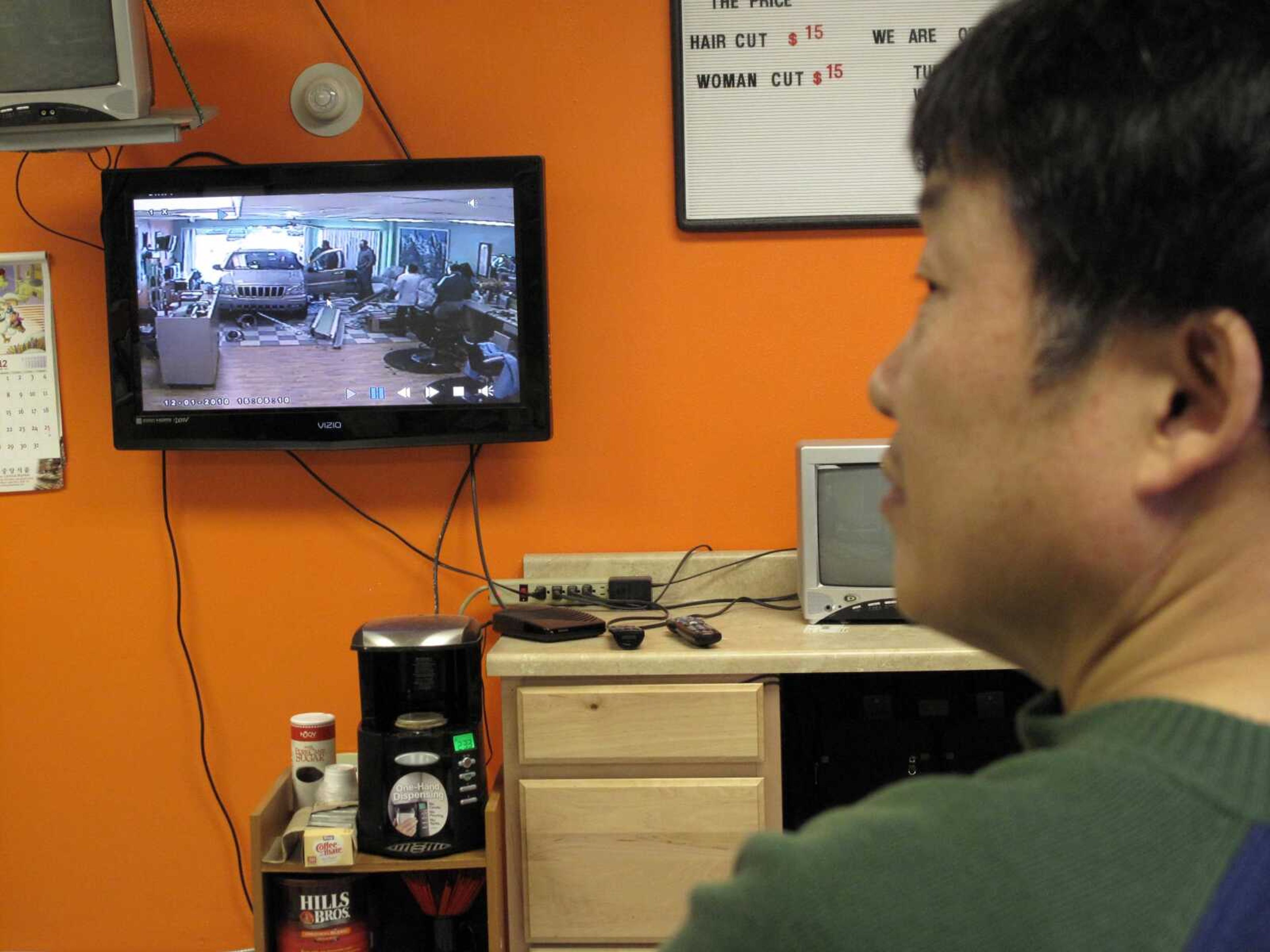 Heng Song recounts the crash of an SUV into his barber shop as he reviews security camera footage Thursday, Dec. 2, 2010, in Anchorage, Alaska. Song was momentarily stunned when the vehicle burst through a door and window Wednesday afternoon as he was clipping a customer's hair. But with no one hurt, and another customer in the shop already notifying police, the 53-year-old shop owner went back to finishing the cut. (AP Photo/Rachel D'Oro)