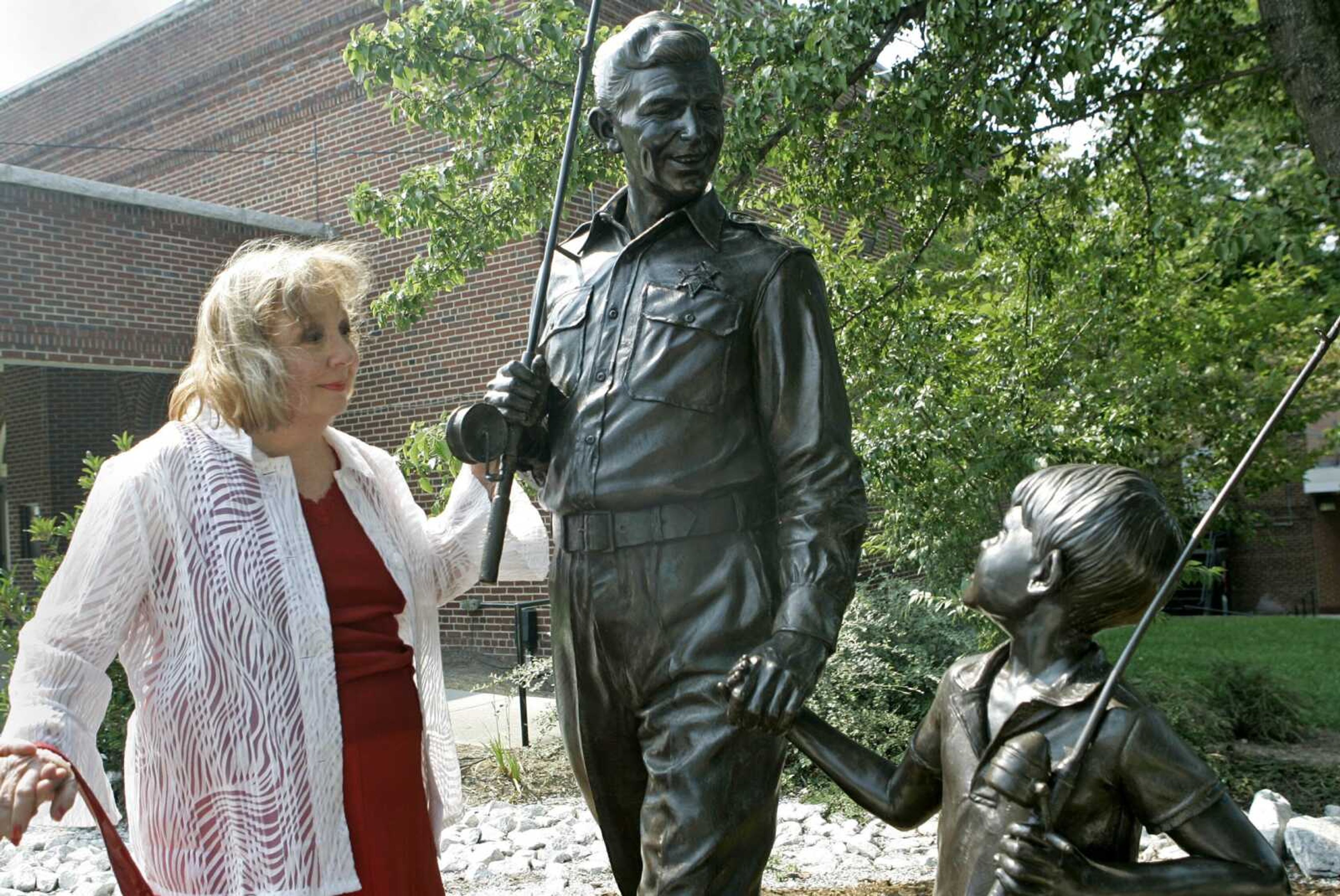 FILE - In this Sept. 6, 2007 file photo, actor Betty Lynn, who played Thelma Lou on  The Andy Griffith Show,  pauses at a statue of Andy and Opie Taylor in Mount Airy, N.C. Lynn died Saturday, Oct. 16, 2021, after a brief illness, The Andy Griffith Museum in Mount Airy announced in a statement.  She was 95.  (AP Photo/Gerry Broome, File)