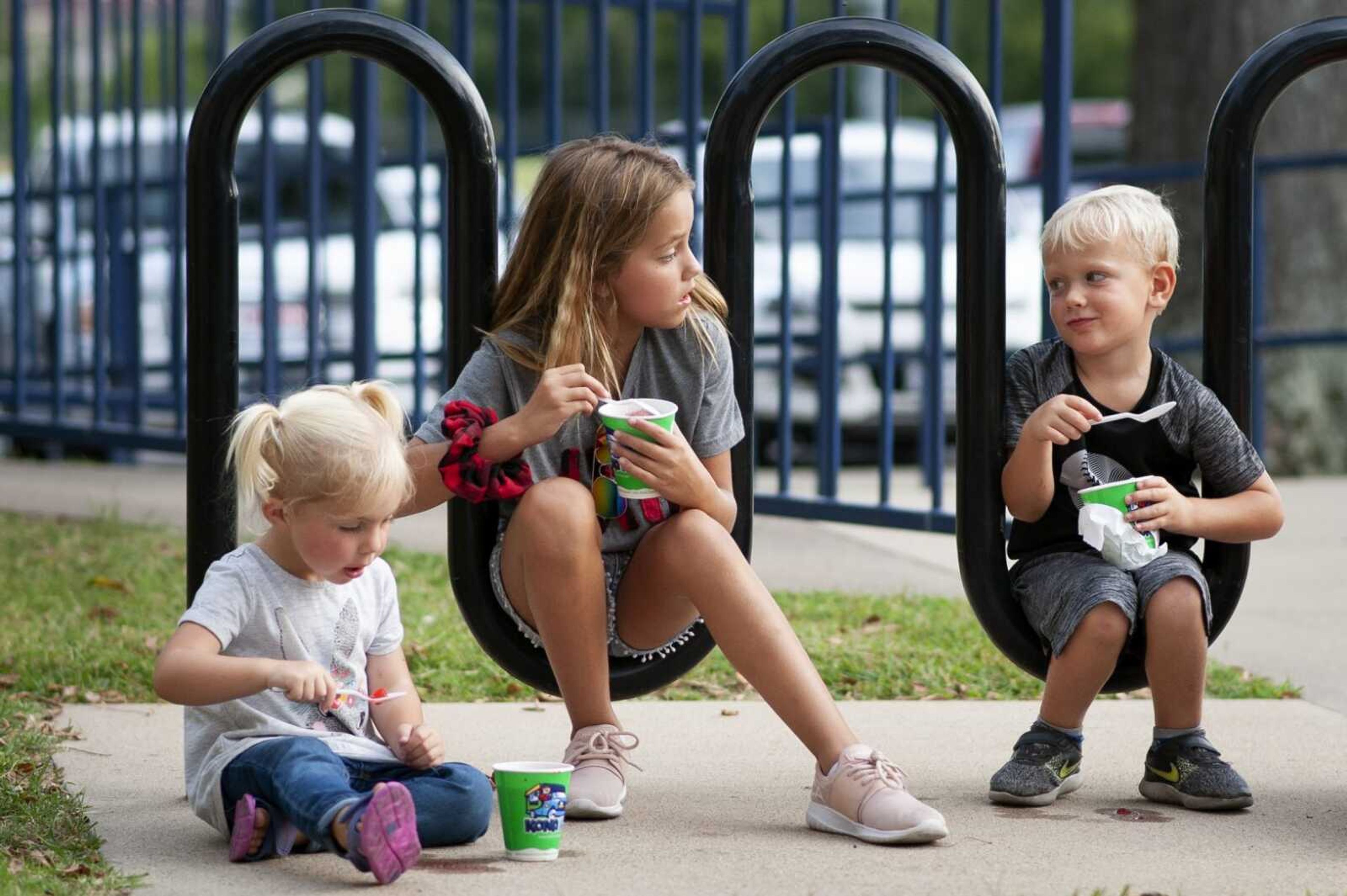 From left, Poppy Clardy, 3, Taelyn Clardy, 8, and Lawson Camp, 3, all of Jackson, eat a snack with Mason Oliver, 10, of Jackson, not pictured, Friday during the 27th annual Cape Jaycees BBQ Fest at Arena Park in Cape Girardeau.