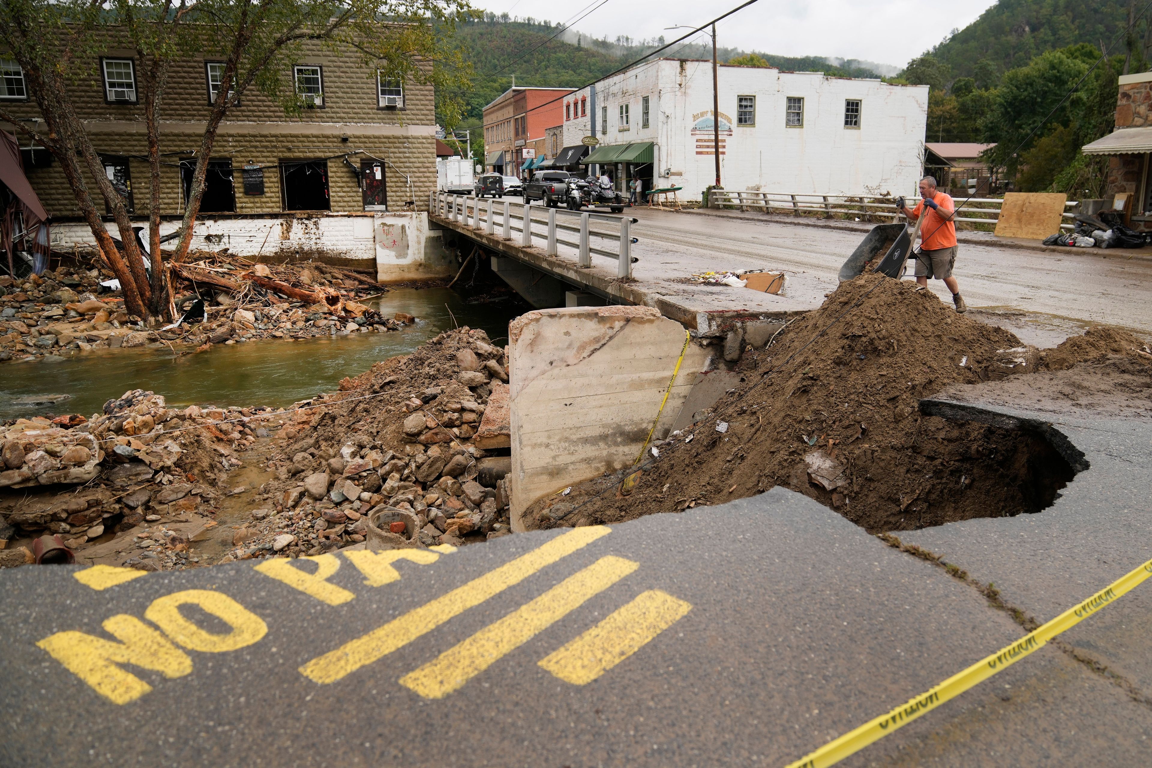 FILE - Len Frisbee dumps a wheelbarrow of dirt as he helps with clean up in the aftermath of Hurricane Helene, Oct. 1, 2024, in Hot Springs, N.C. (AP Photo/Jeff Roberson, File)