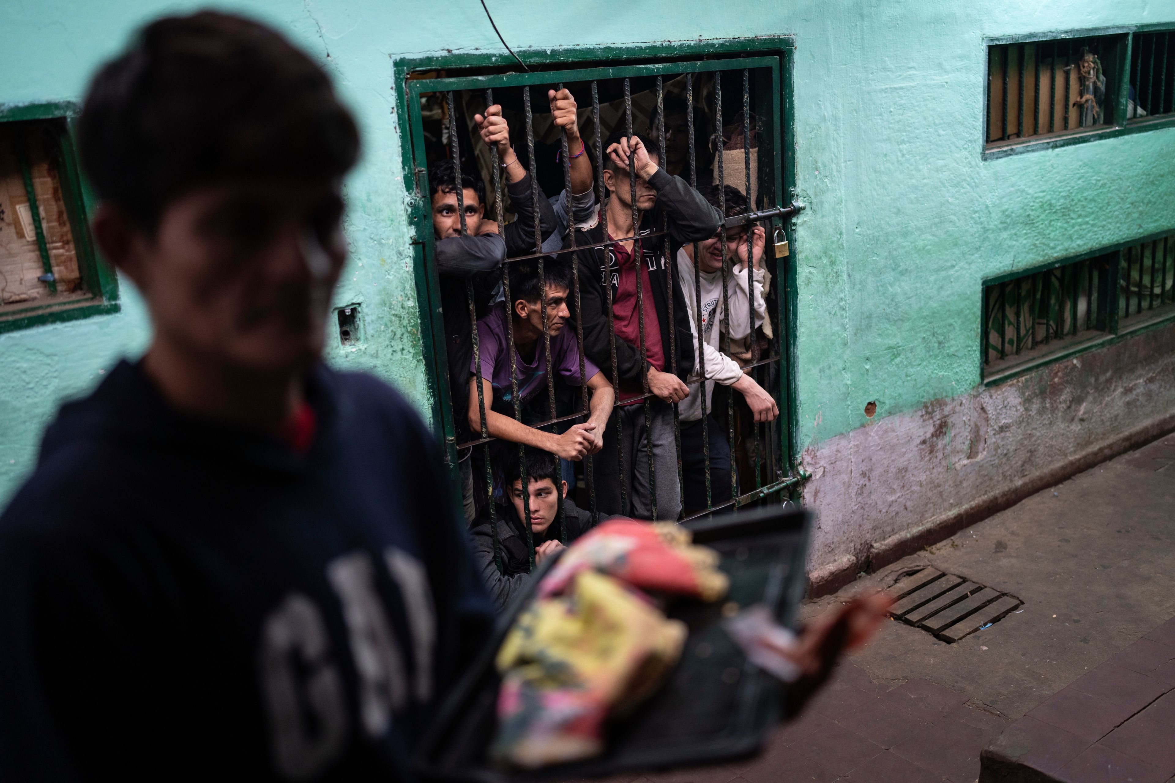 Prisoners peer from their group cell in the late afternoon, to be unlocked in the morning, as another prisoner prepares to enter another group cell to be locked for the night at the Regional Penitentiary in Villarica, Paraguay, Saturday, Aug. 31, 2024. (AP Photo/Rodrigo Abd)