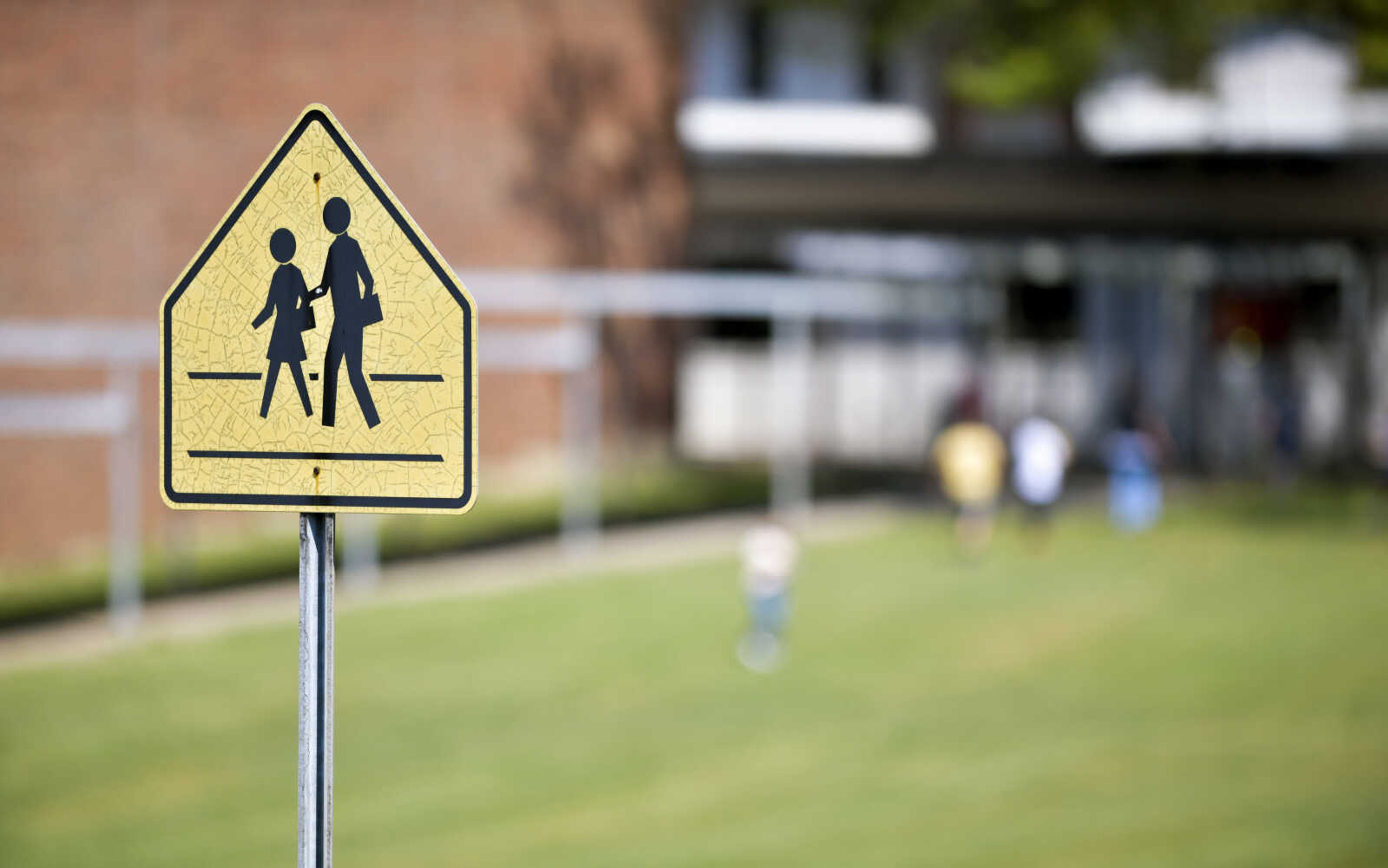 A school crossing sign stands in front of the Terry W. Kitchen Central Junior High School as students play on the lawn Monday, Aug. 24, 2020, in Cape Girardeau.