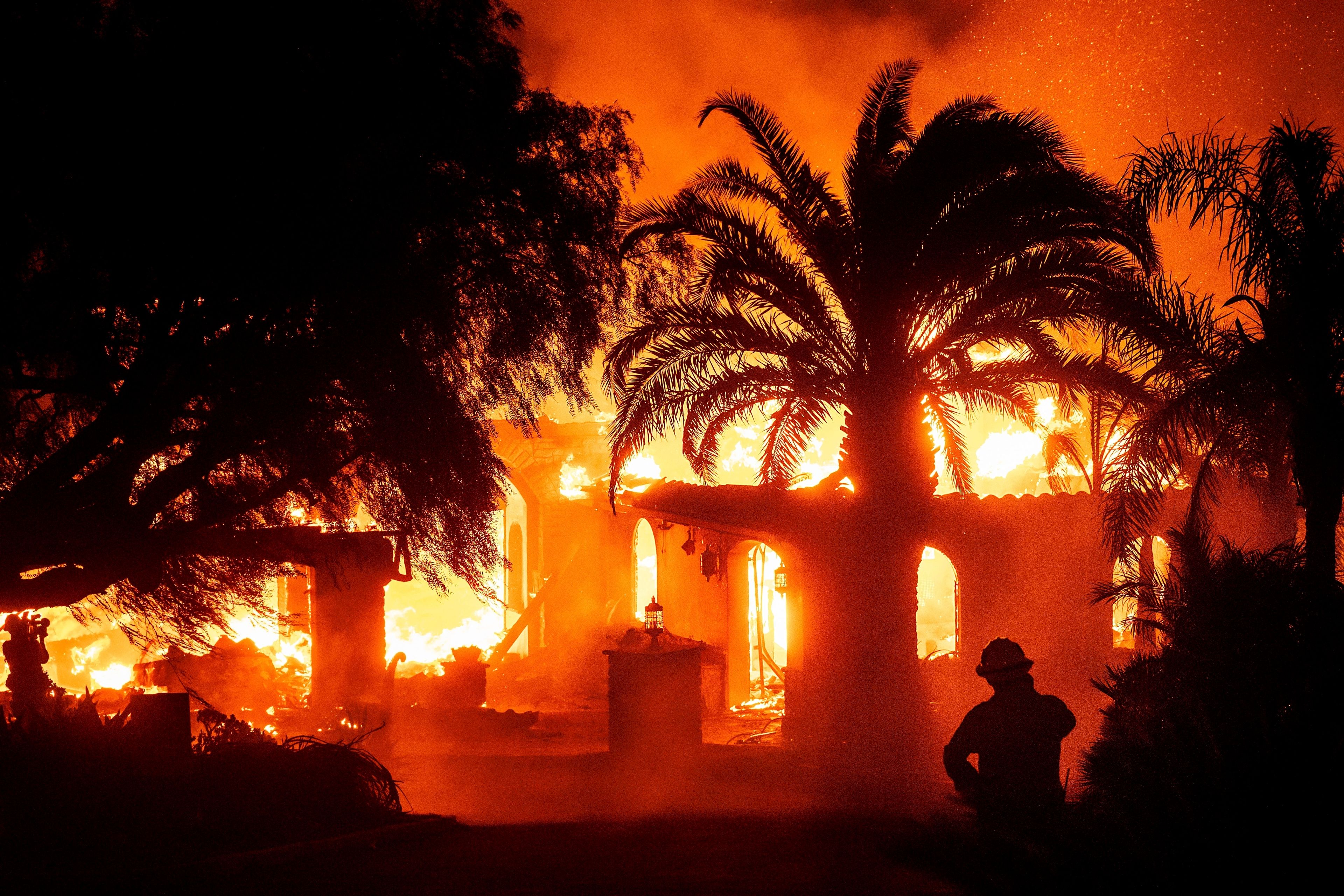 A firefighter watches as flames from the Mountain Fire consume a home in Camarillo, Calif., Nov. 6, 2024. (AP Photo/Noah Berger)